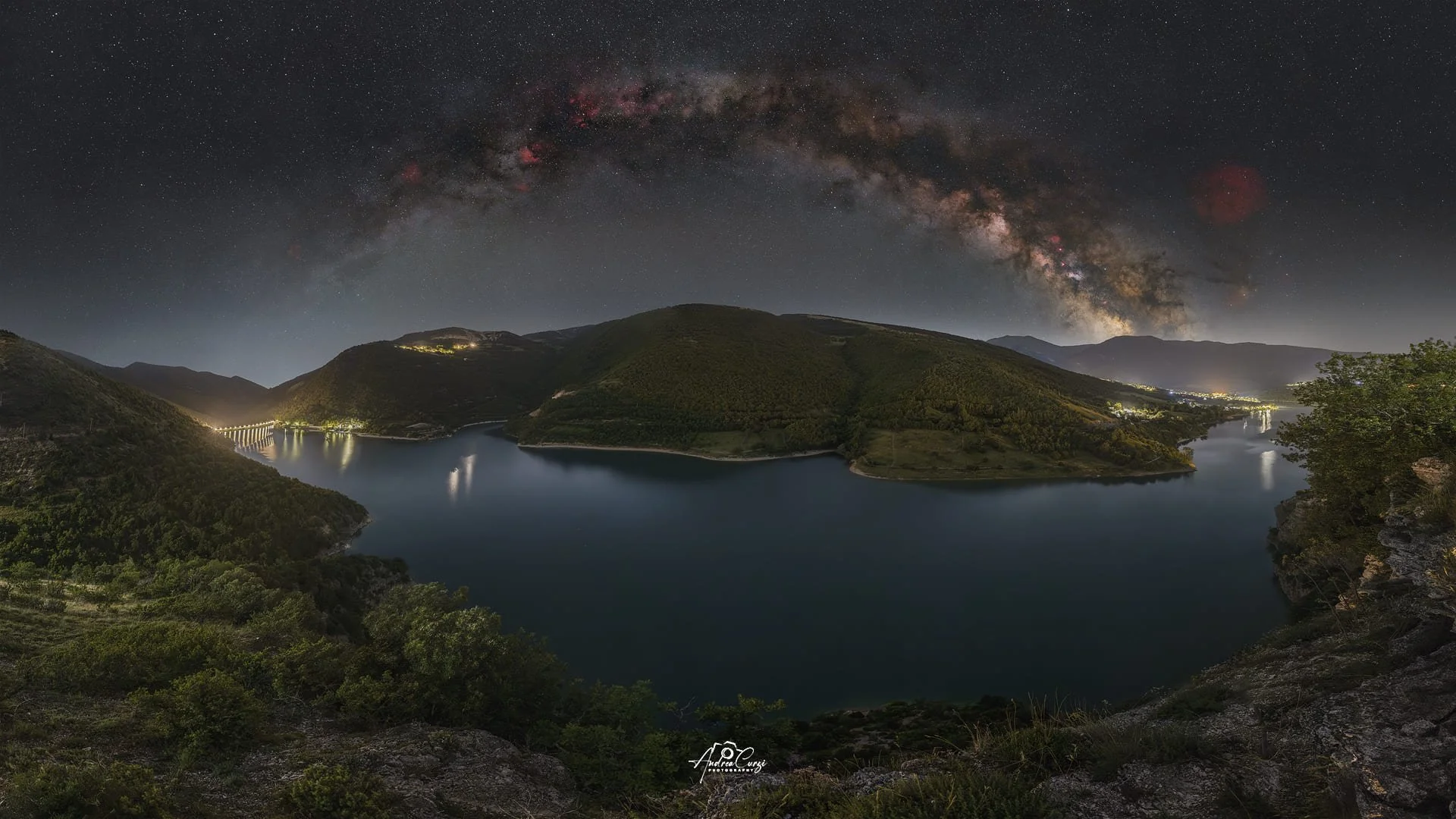 Vista notturna di un lago tra le montagne con il cielo stellato e l'arco estivo della via Lattea. Siamo sui Monti Sibillini, sul lago di Fiastra.