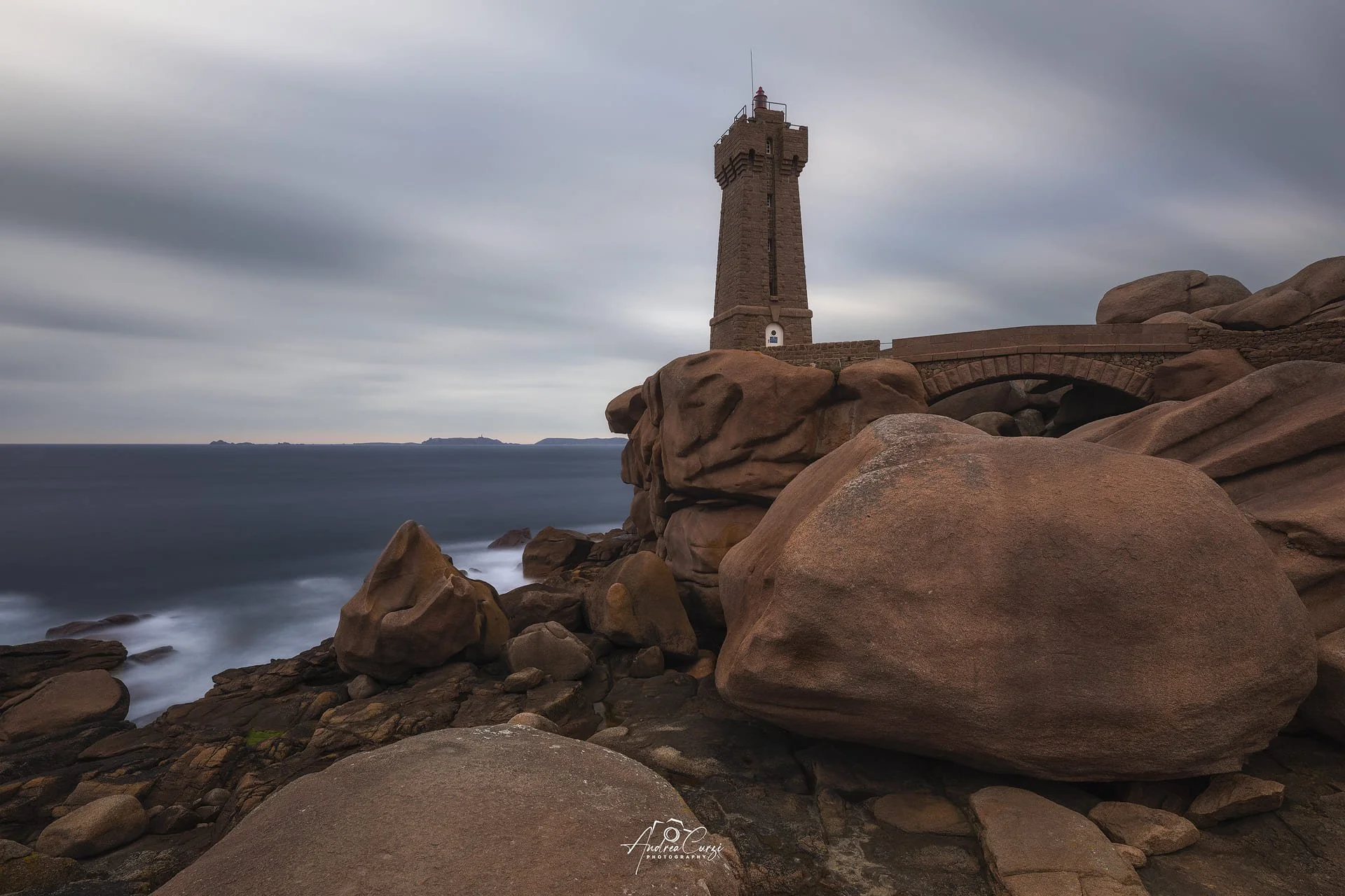 Faro di Ploumanac'h in Bretagna con rocce sulla costa di granito rosa e mare sotto un cielo nuvoloso