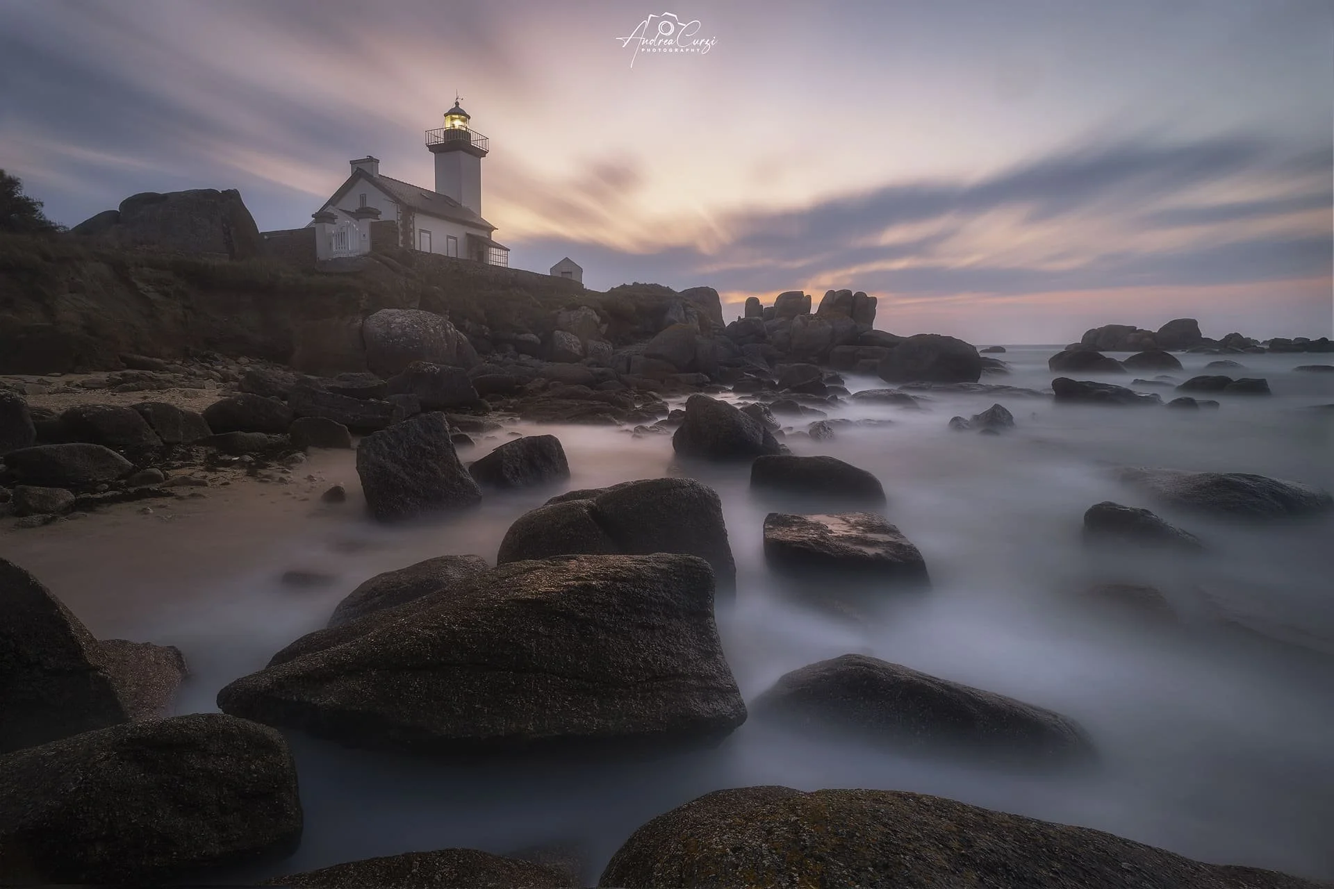 Faro di Pontusval in Bretagna sulla scogliera al tramonto con acqua liscia sulle rocce