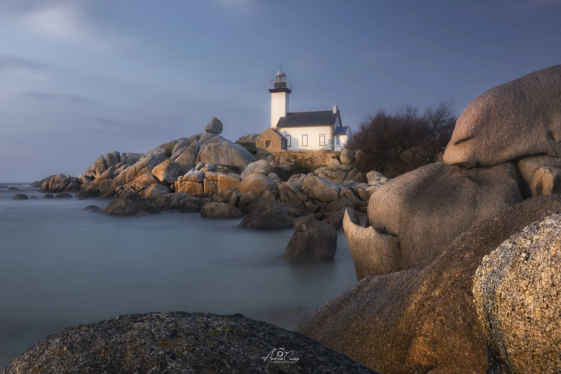 Faro di Pontusval in Bretagna con scogli al mare con cielo nuvoloso