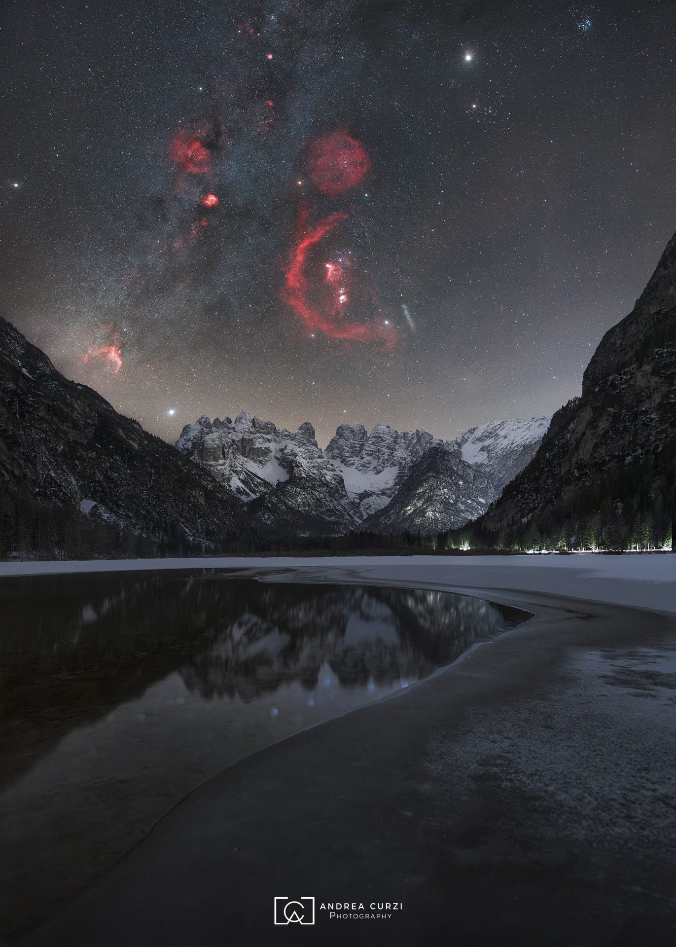 Foto notturna della Via Lattea invernale con la nebulosa di Orione al Lago di Landro in Dolomiti. Scattata durante un viaggio fotografico di Andrea Curzi