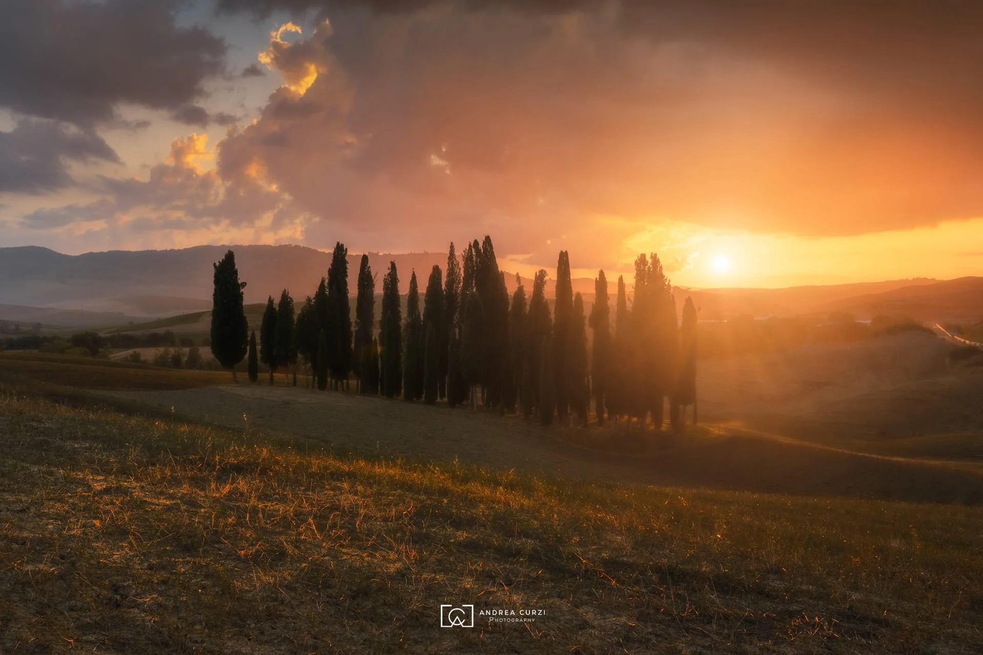 Paesaggio toscano al tramonto con cipressi e colline. Scattata in Val d'Orcia in Toscana durante un workshop fotografico 1to1 di Andrea Curzi.