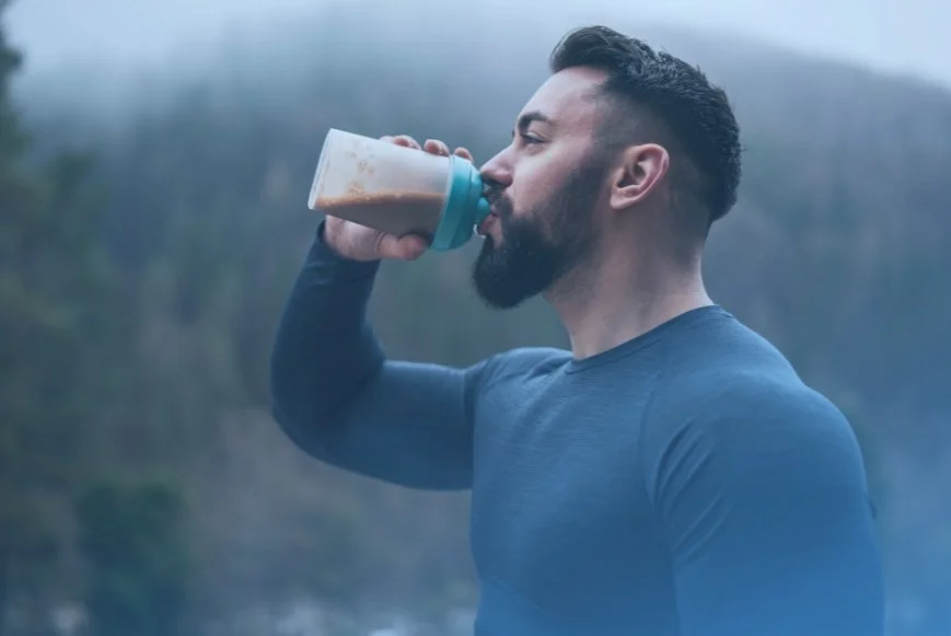 Fit man drinking protein shake. Information about importance of protein for body and brain health at DexaFit West Houston, TX