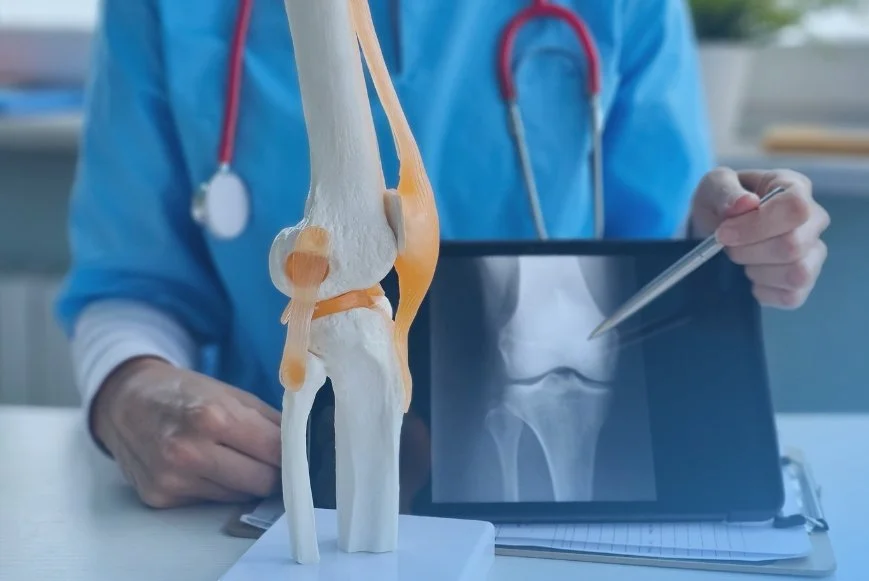 Doctor holding knee bone model and X-ray image demonstrating bone density scan using DexaFit Body Scan, at DexaFit West Houston TX