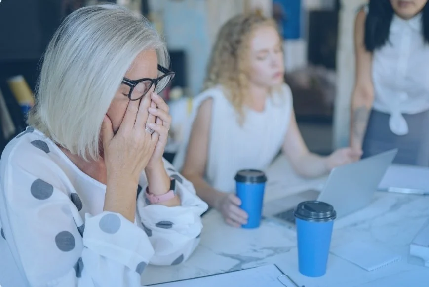 Middle aged woman in business meeting rubbing eyes. Fatigue or aging- testing at DexaFit West Houston, TX
