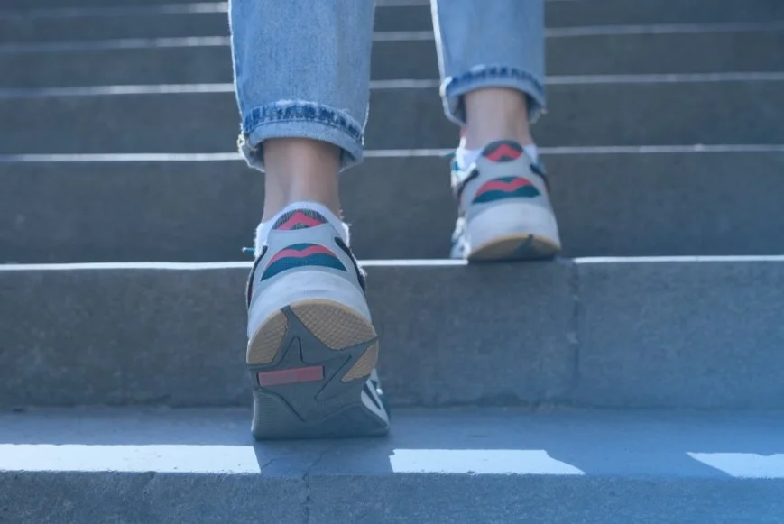 Close up of person's feet walking up stairs. Representing functional fitness improvement at DexaFit West Houston, TX