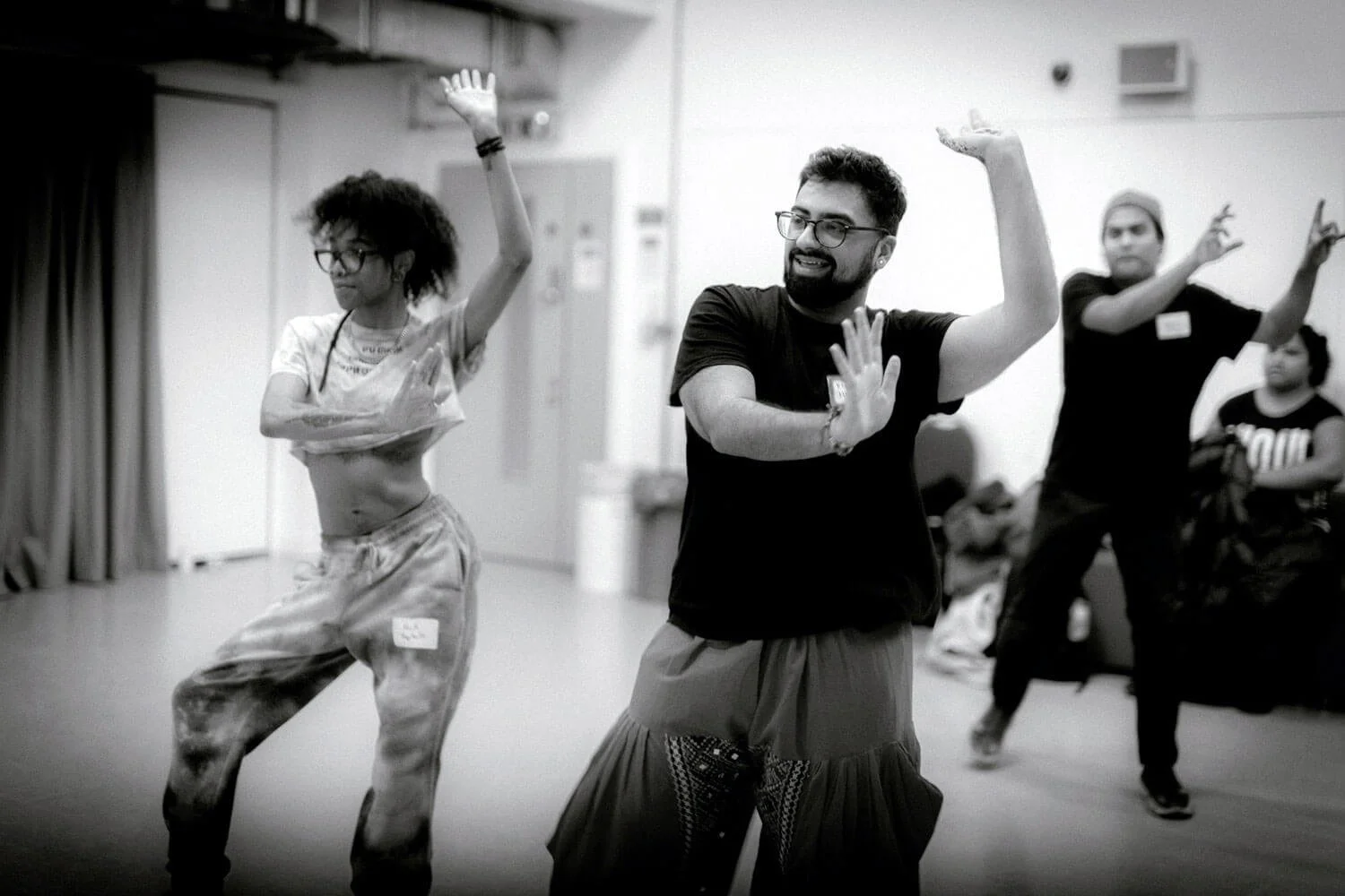 Group of diverse people dancing together in a dance class or rehearsal space, smiling and enjoying the activity.