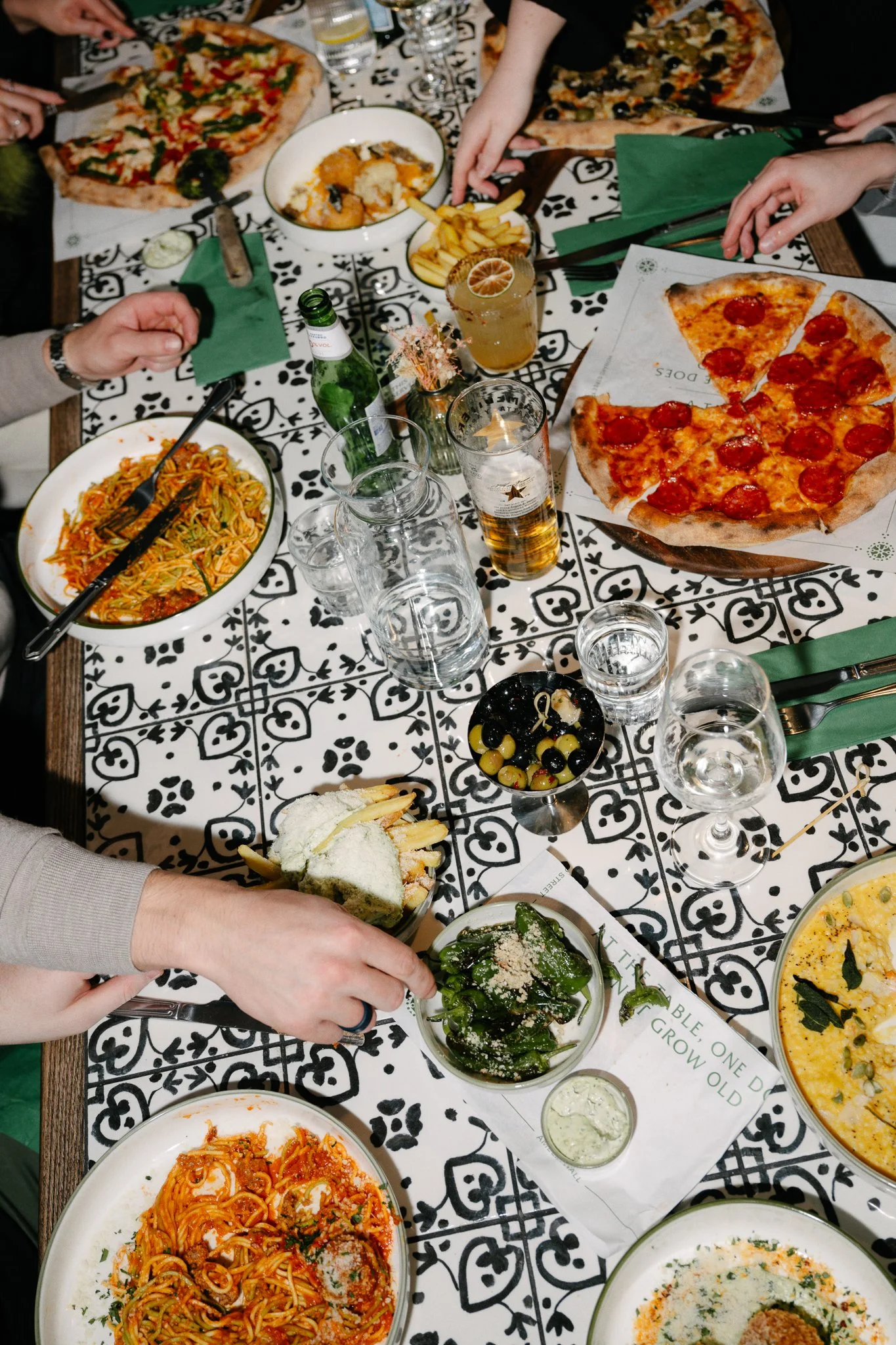 Friends sharing pizza, pasta and small plates with cocktails and beer at Amelia Hall on Howard Street, Belfast.
