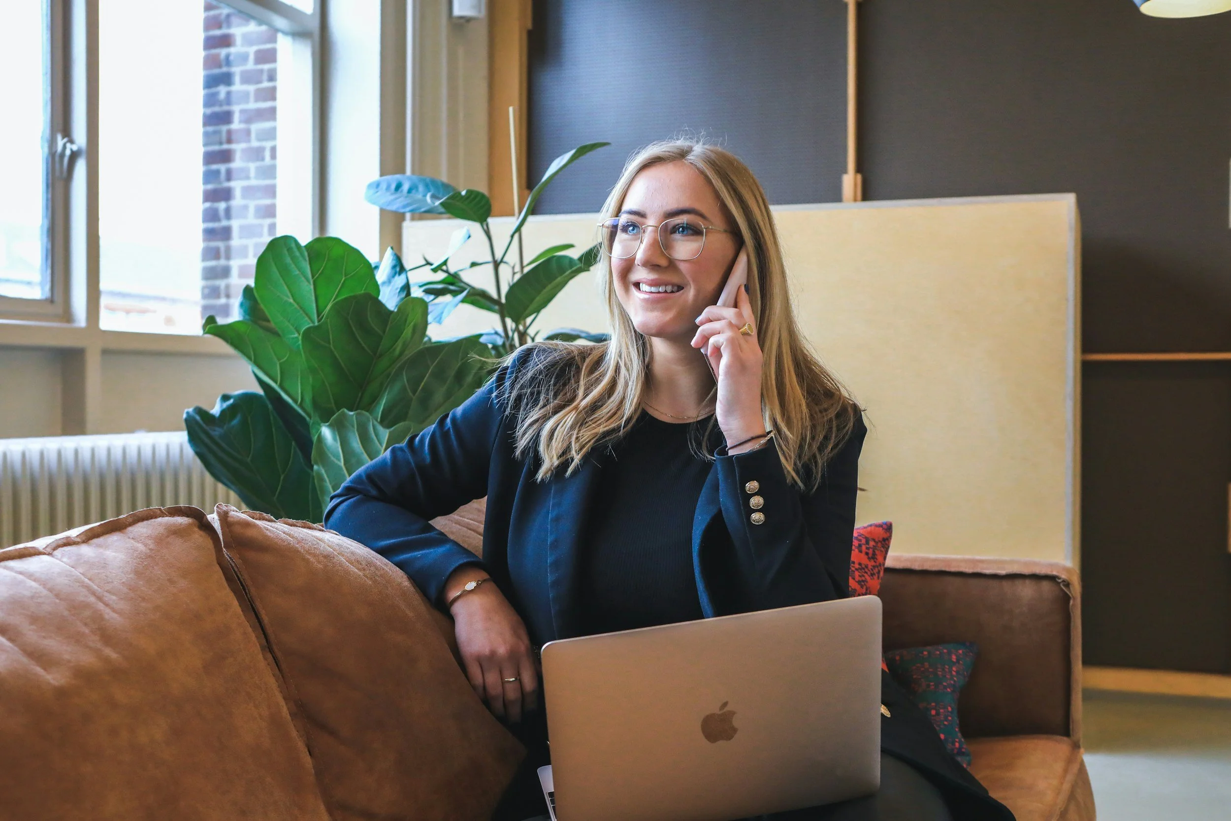 Young blond women on the phone with her business coach with her apple computer in her lap.