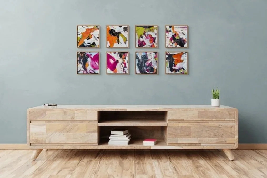Collection of small abstract artworks from the 5700 Miles From Sausalito series, hanging above a long cabinet
