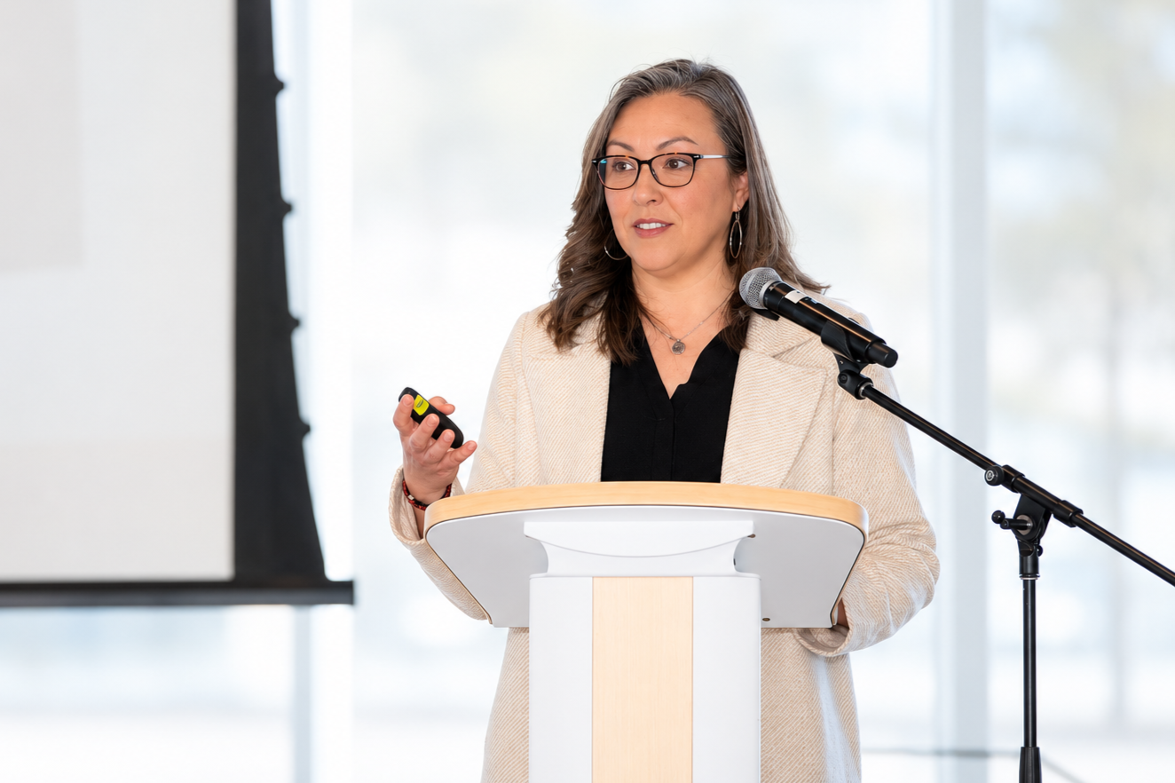 Woman giving a presentation at a podium with a microphone, holding a remote control