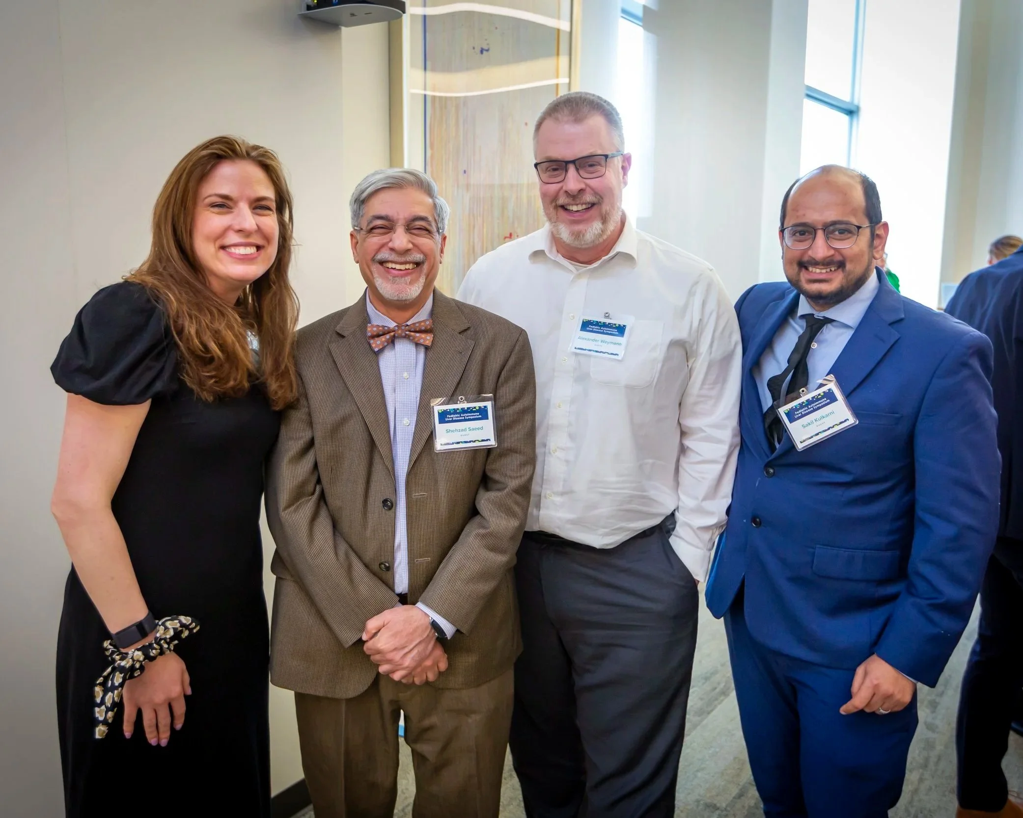 Four people standing together at an indoor event and smiling at the camera.