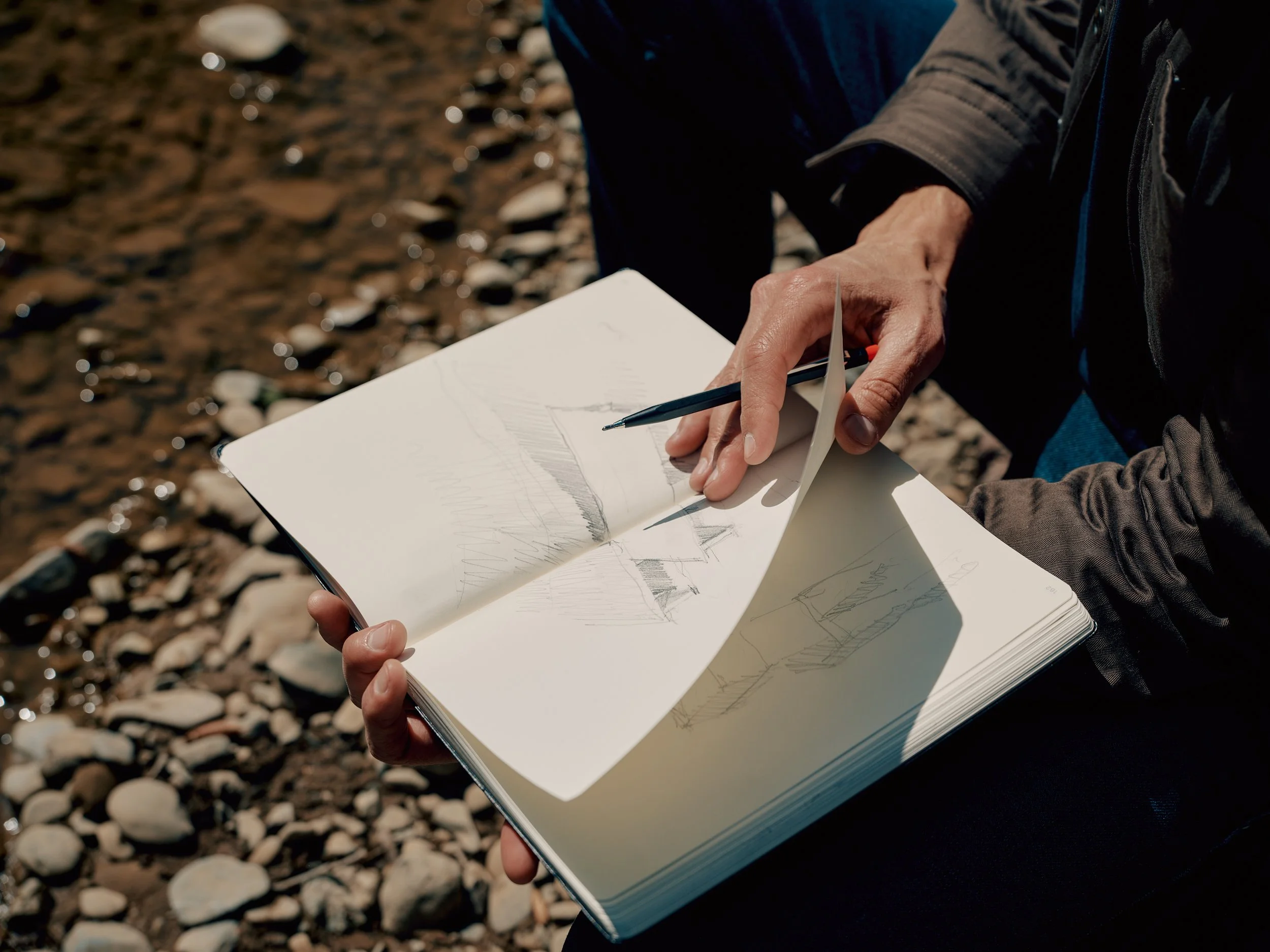 Architect Jess Field holding a notebook with sketches of landscapes and designs