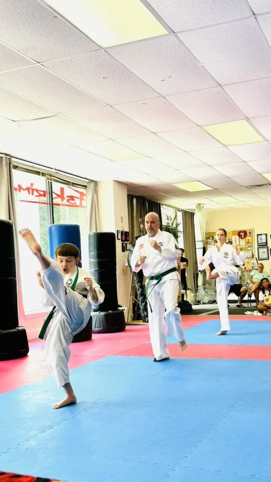 Children practicing martial arts in a dojo with spotlights, mats, and instructors.