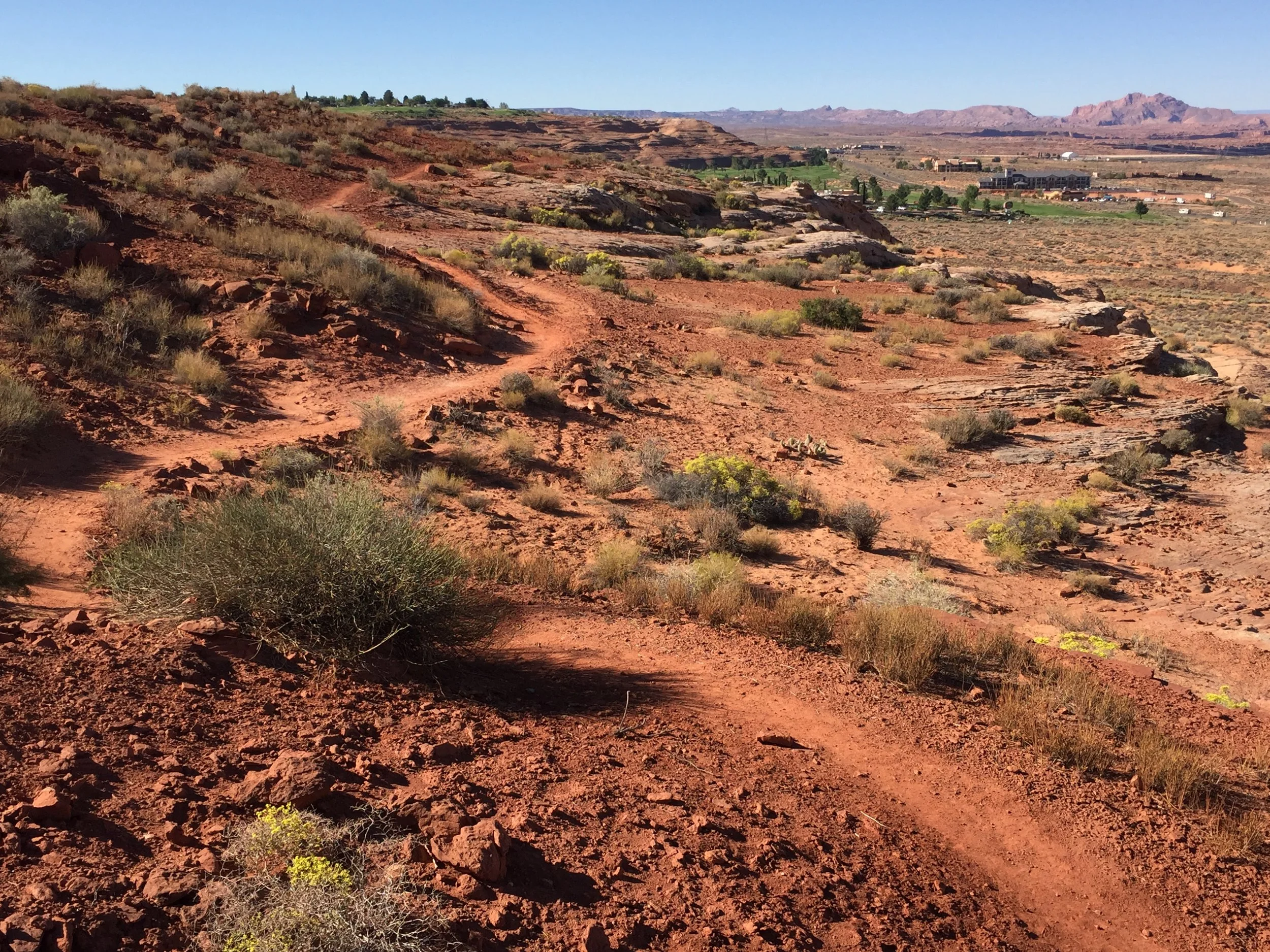 Page Rim Trail winding through red sandy desert scenery with buildings in the distance