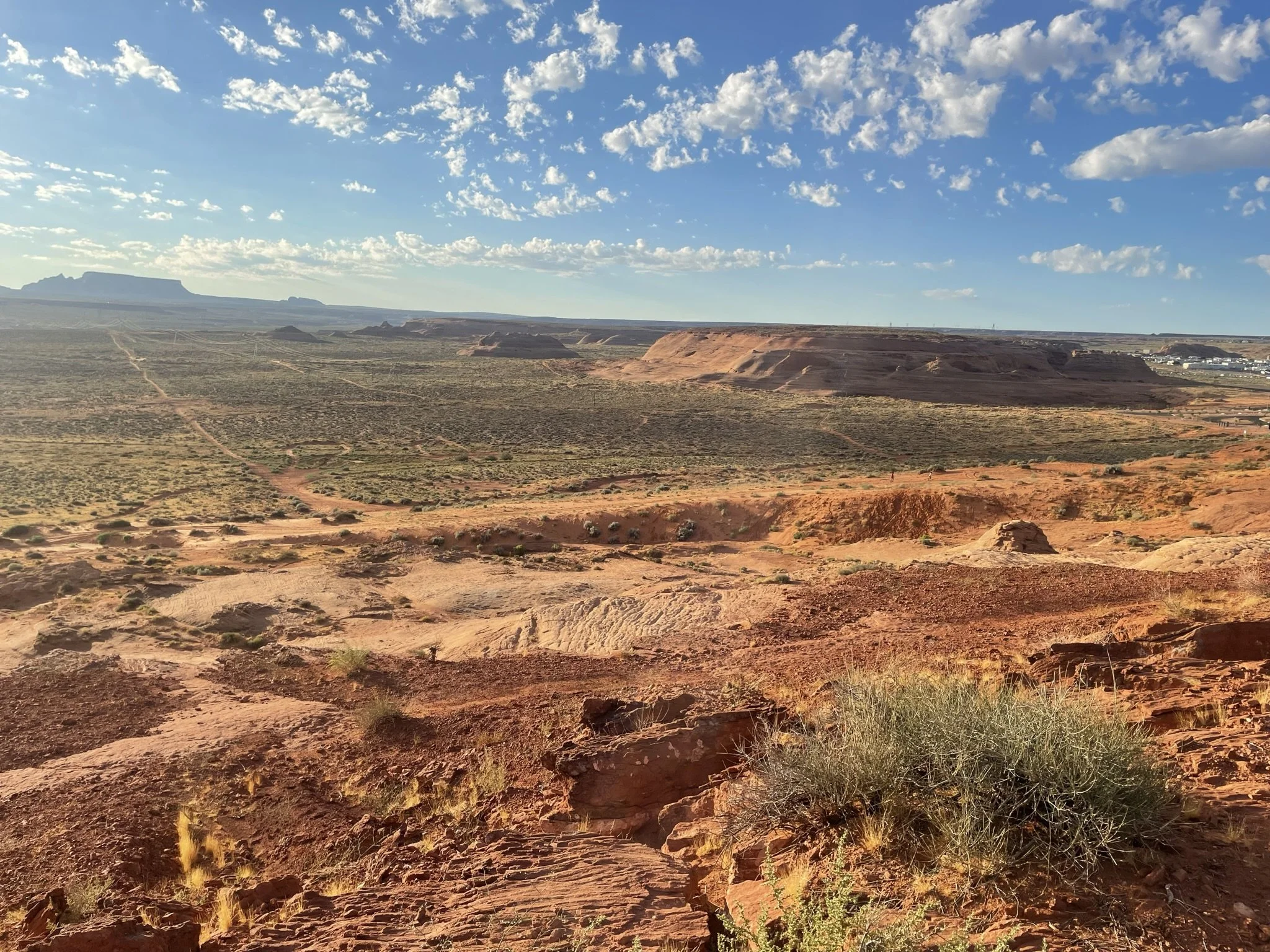 Panoramic red sandstone desert view with roads and distant hikers along Page Rim Trail