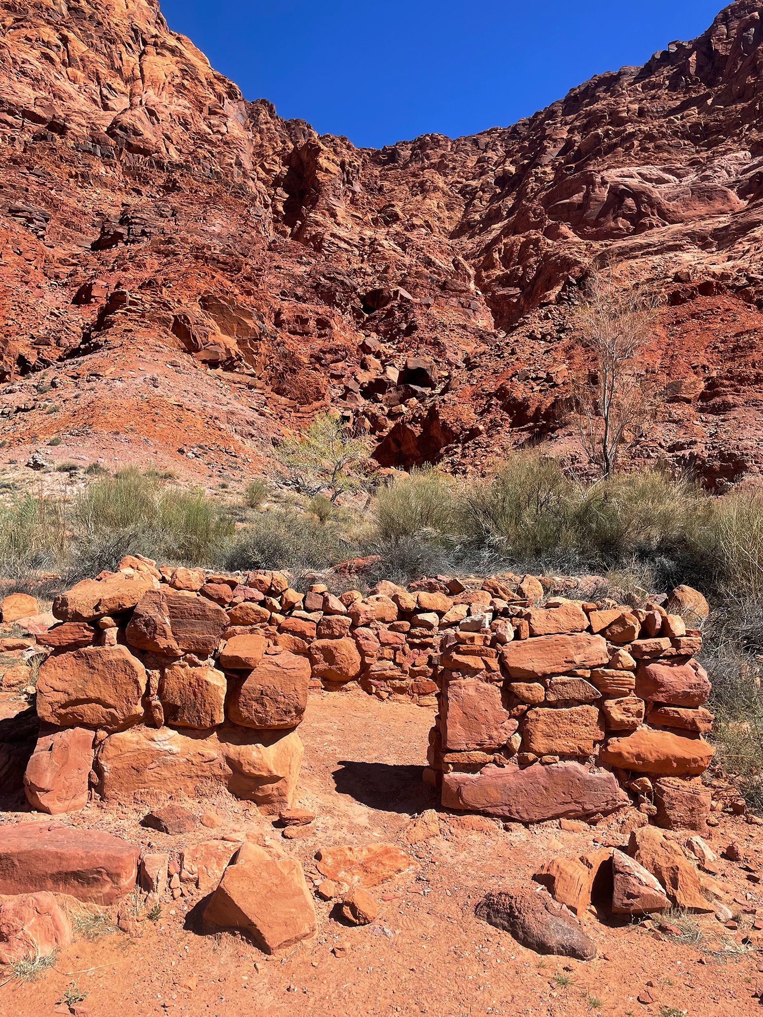 Ruins of stone structure in re rock canyon terrain