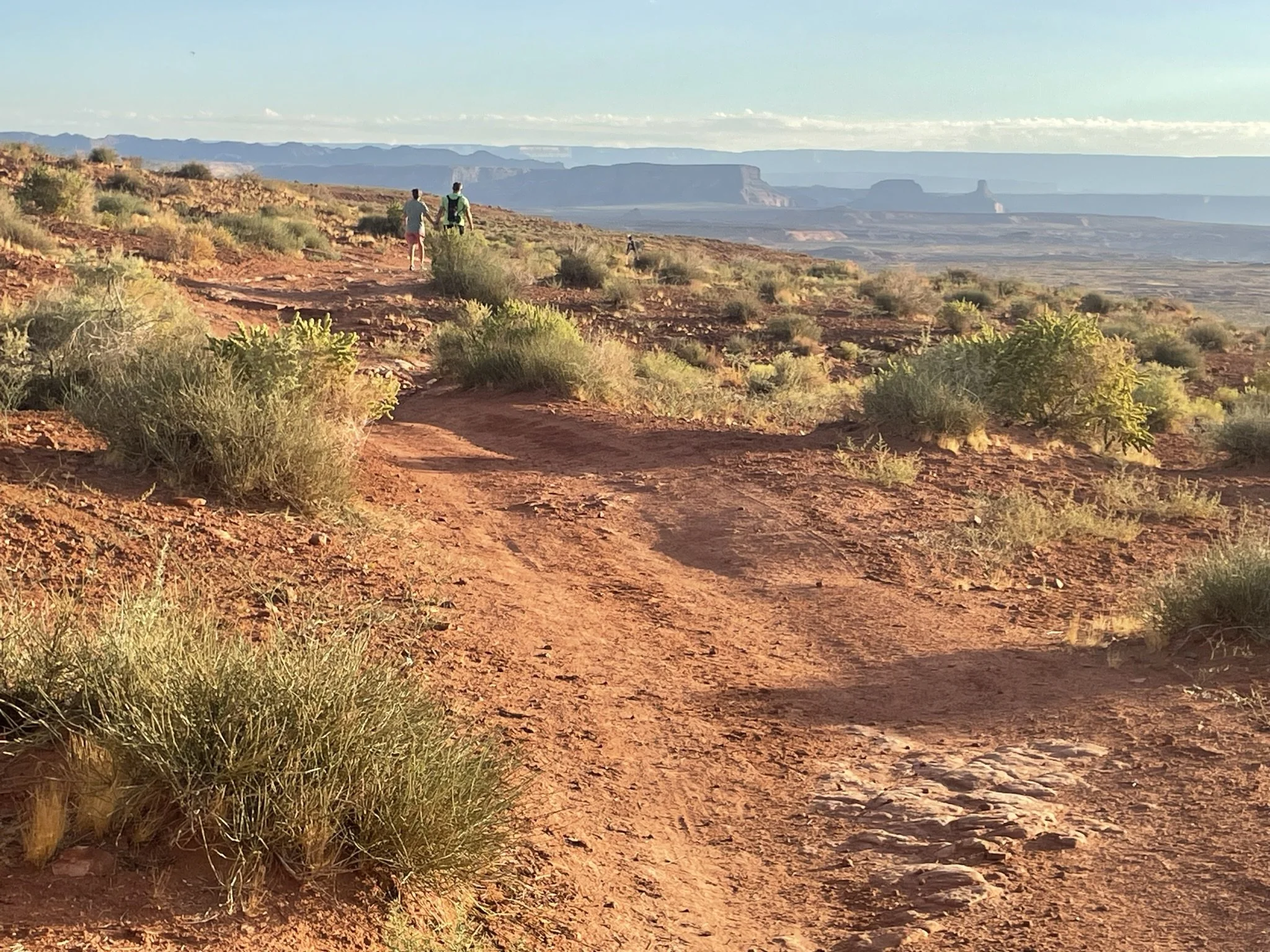 Two hikers on Page Rim Trail with distant cliffs and buttes