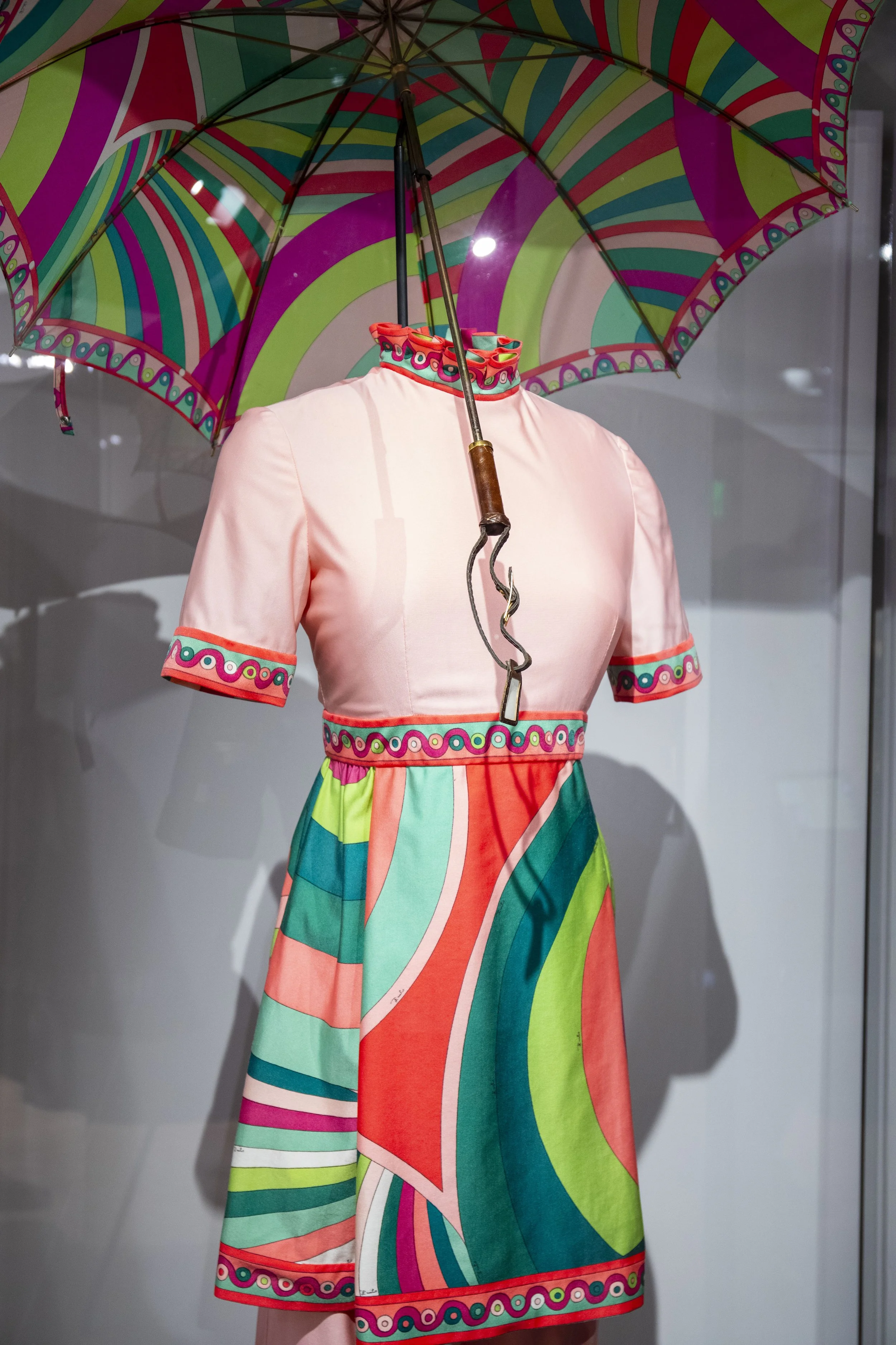 a colorful flight attendant uniform with pink and lime green designs, complete with umbrella.