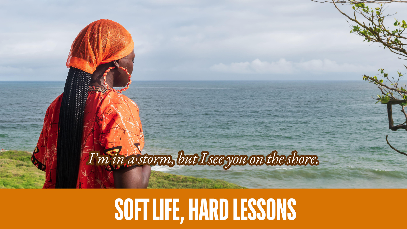 Black woman in an orange shirt, orange hoop earrings, and orange head wrap pausing. She stands on grass in front of a large body of water. White letter overlay with brown outline: "I'm in a storm, but I see you on the shore."