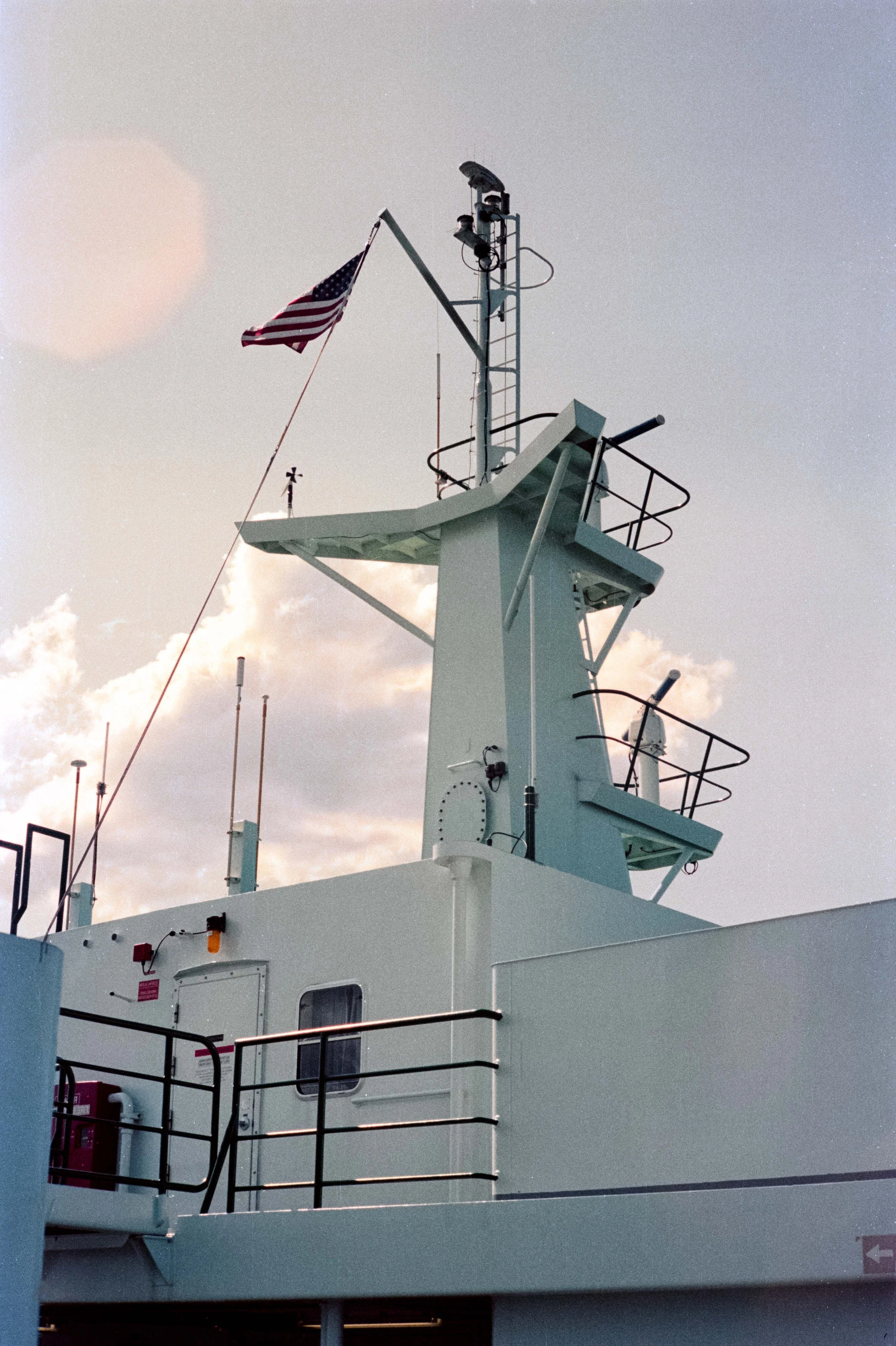 top of a ship with a US flag waving and two tiers of a crow's nest with telescopes and intruments