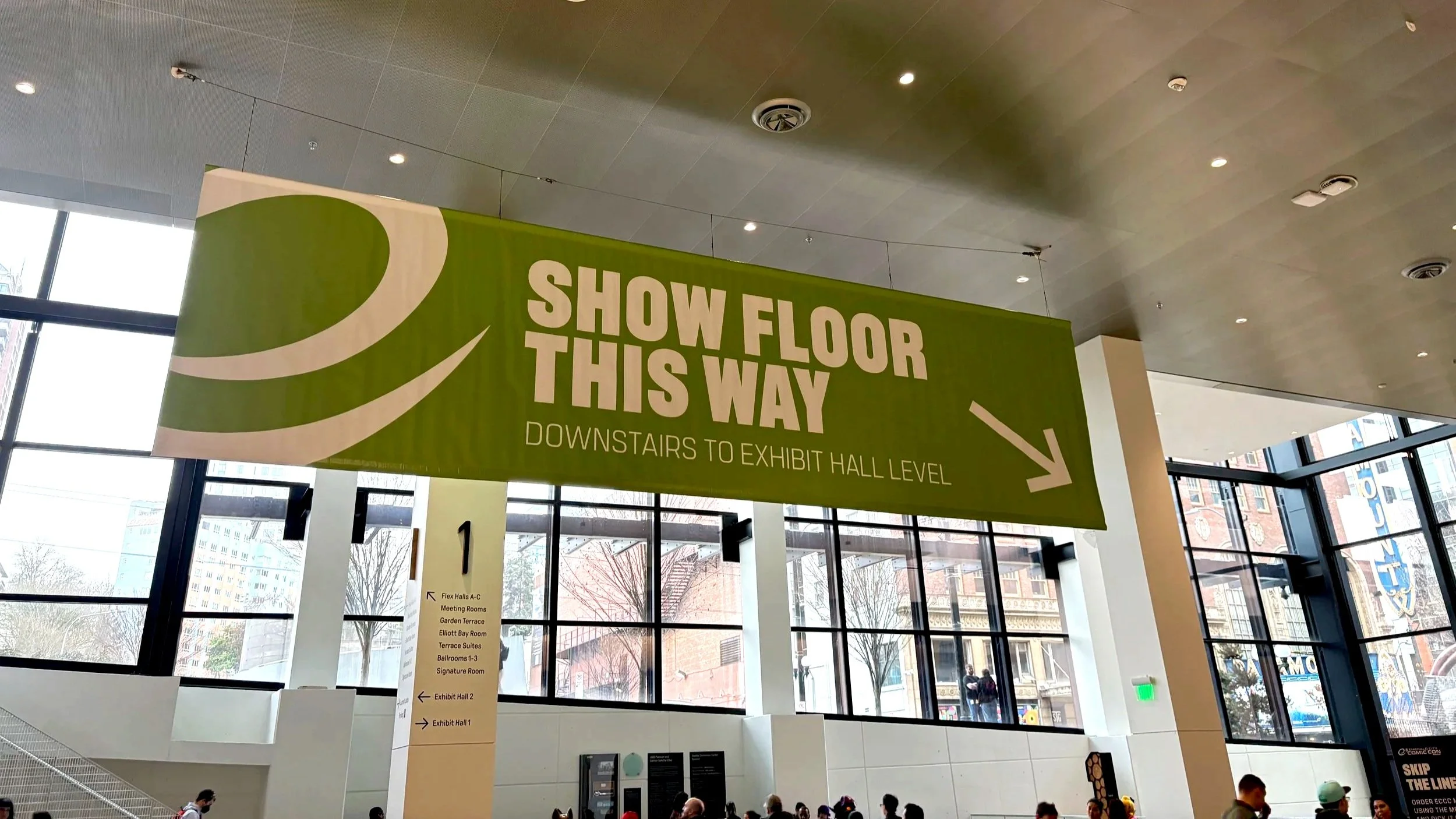 ECCC directional green banner pointing downward to Show Floor at Summit Building; windows behind banner