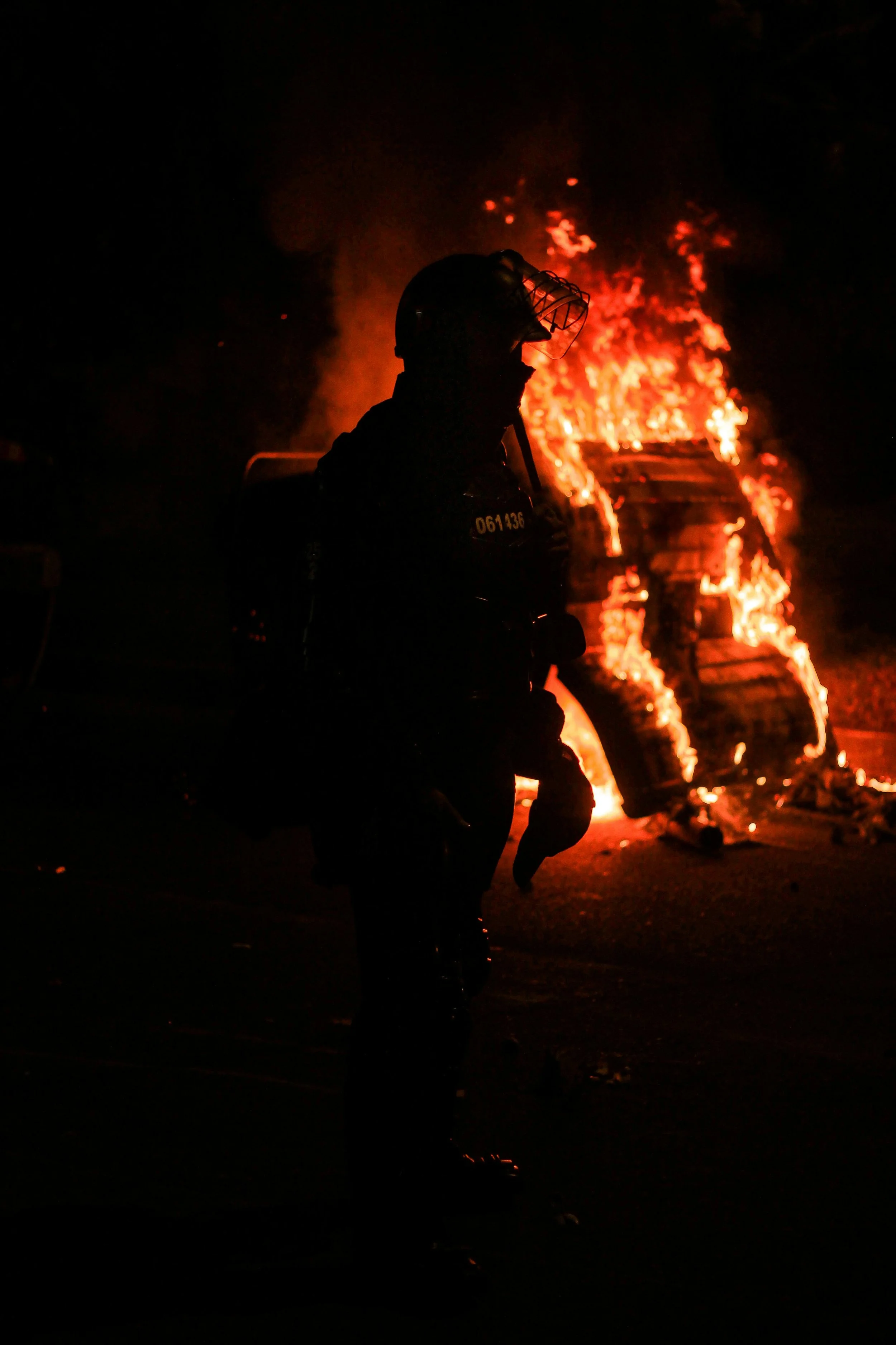 riot cop in front of a bonfire in the dark