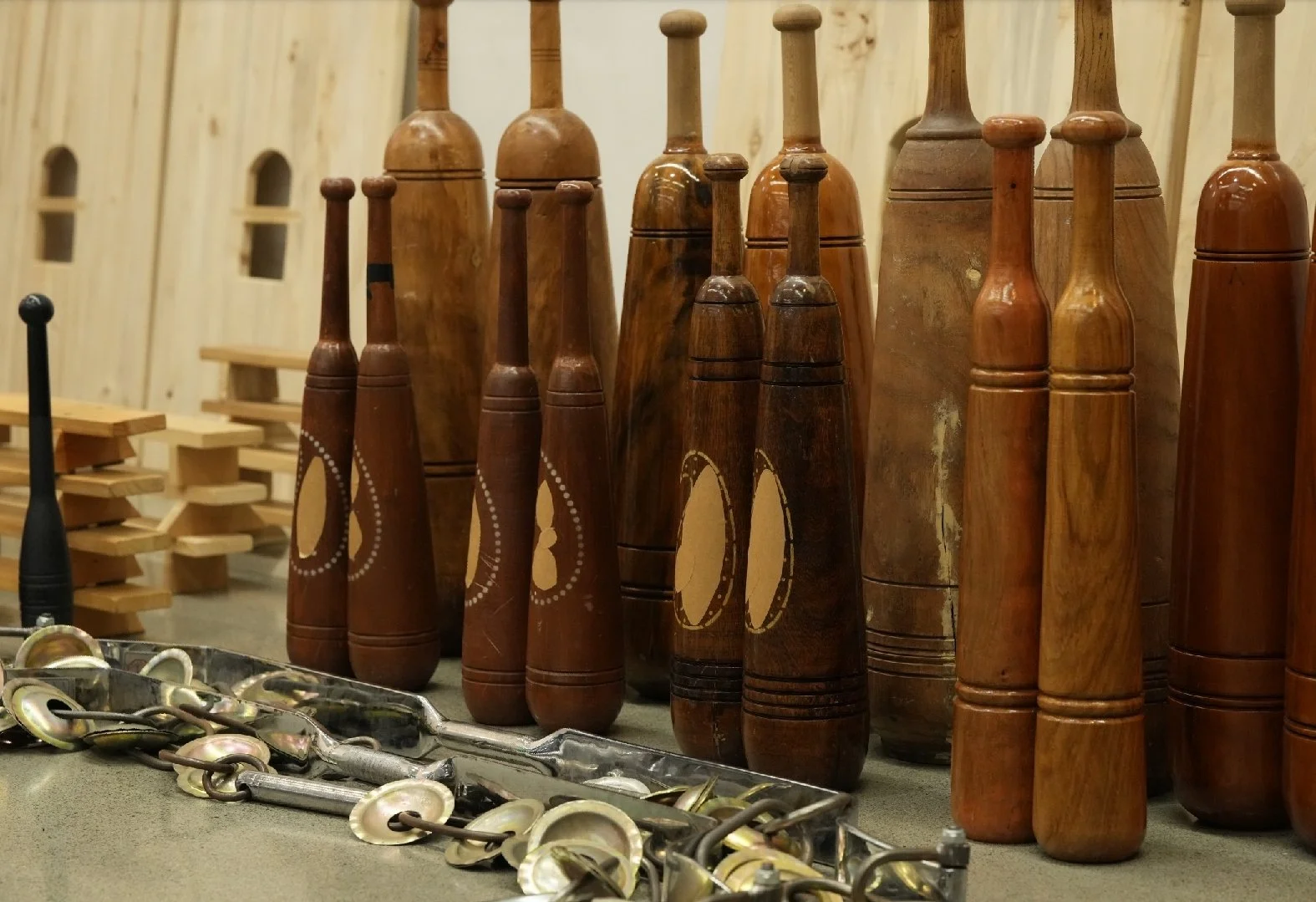rows of standing mil (Indian clubs), varying sizes and wooden colors