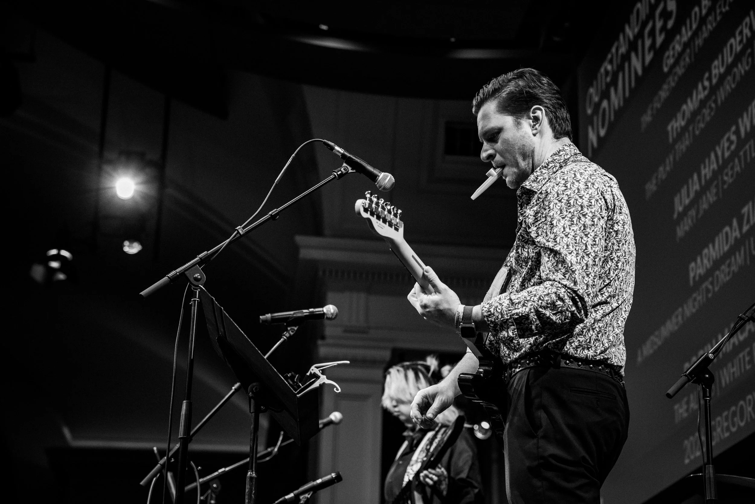 guitarist on stage at a mic with kazoo in his mouth