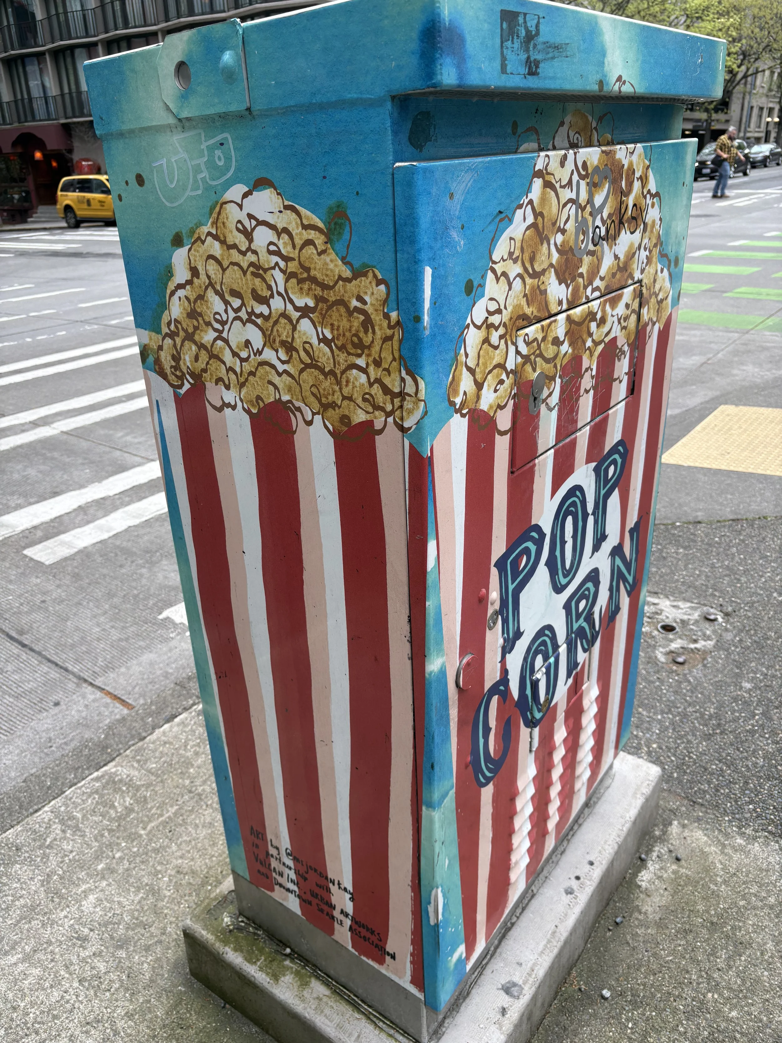 utility box painted with light blue background and classic theater popcorn in red and white striped cartons