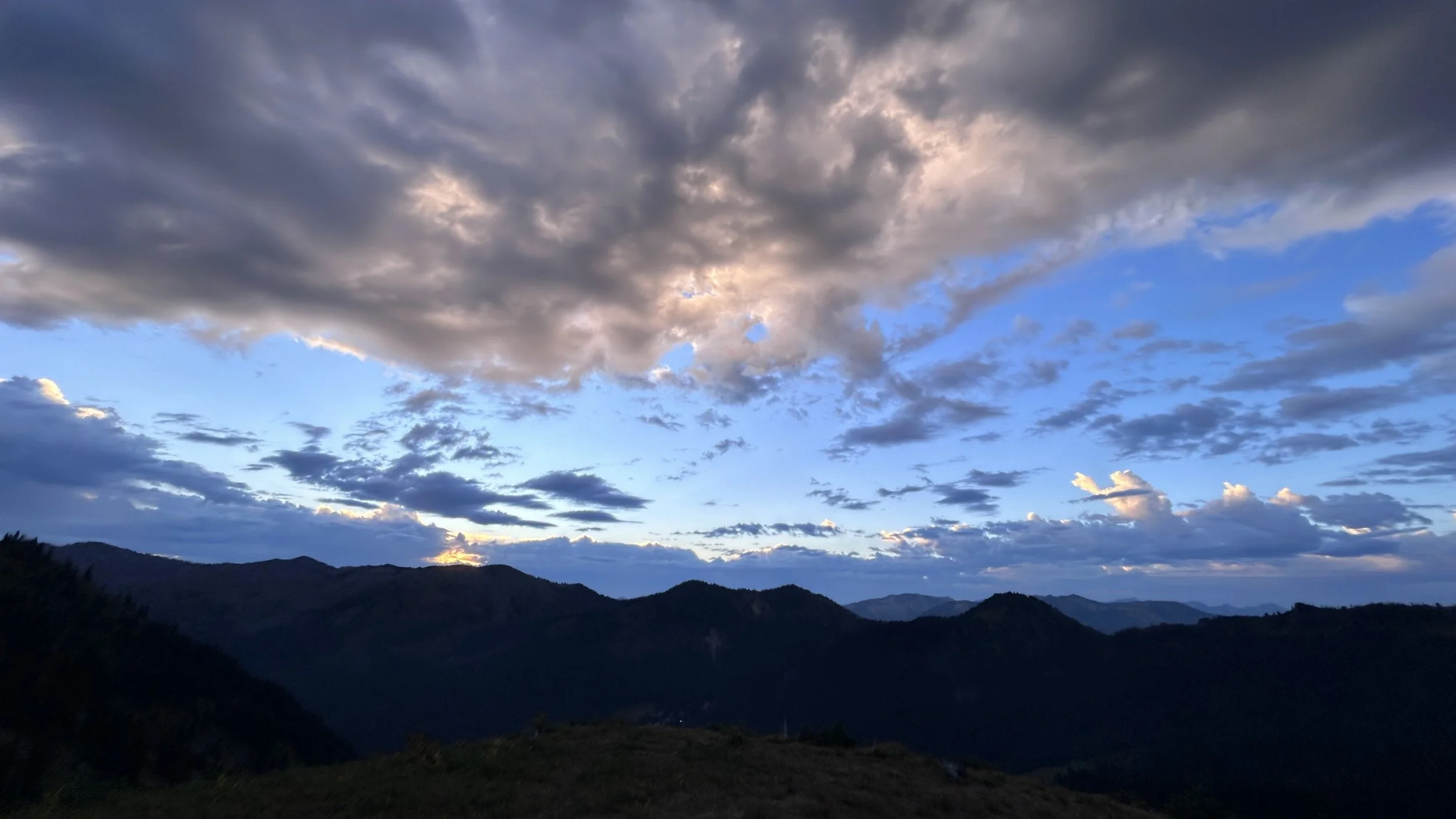 sunrise with blue skies and wispy clouds from the top of a mountain peak