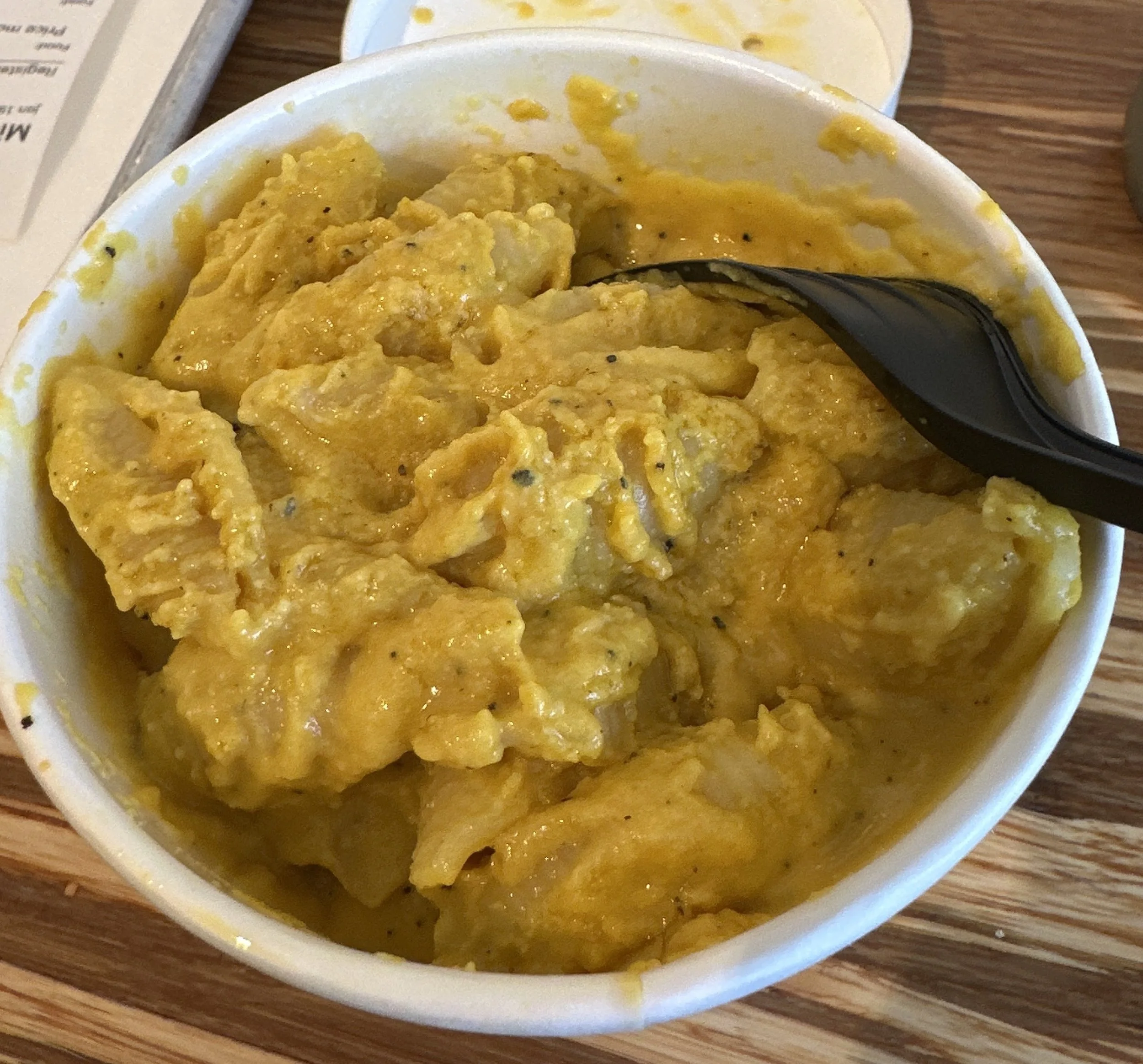 close up of Cafe Red's vegan mac n cheese, black compostable fork leaning into it on right