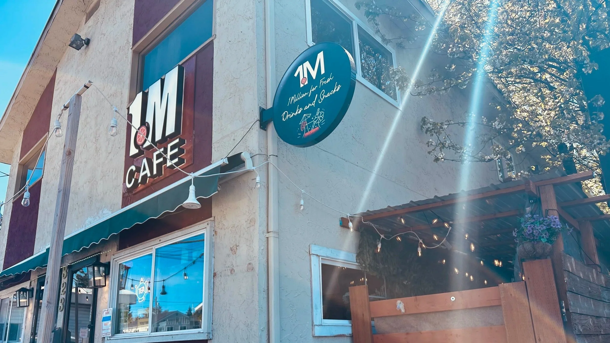 facade of 1 Million Cafe with string of lights, signage, patio on right side