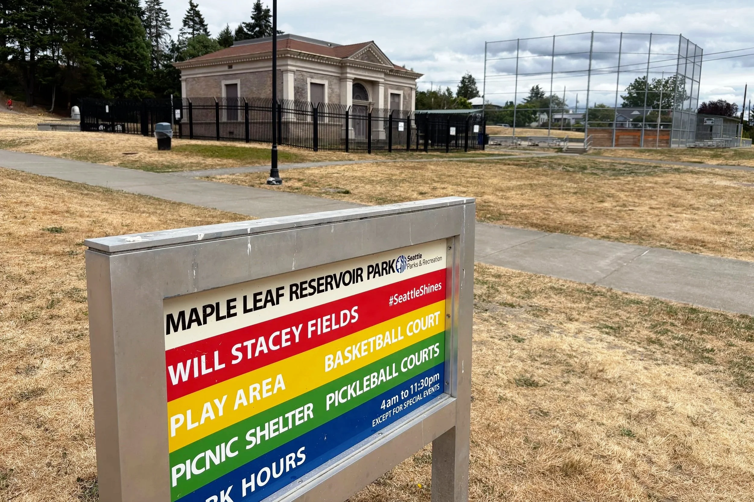 Maple Leaf Reservoir Park sign, the reservoir building in the background alongside a tall playfield fence