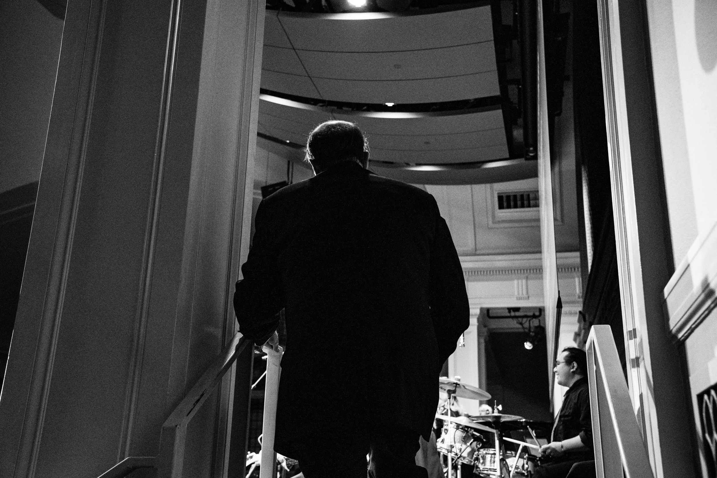 man with back to camera awaits cue to step on stage with winner envelope