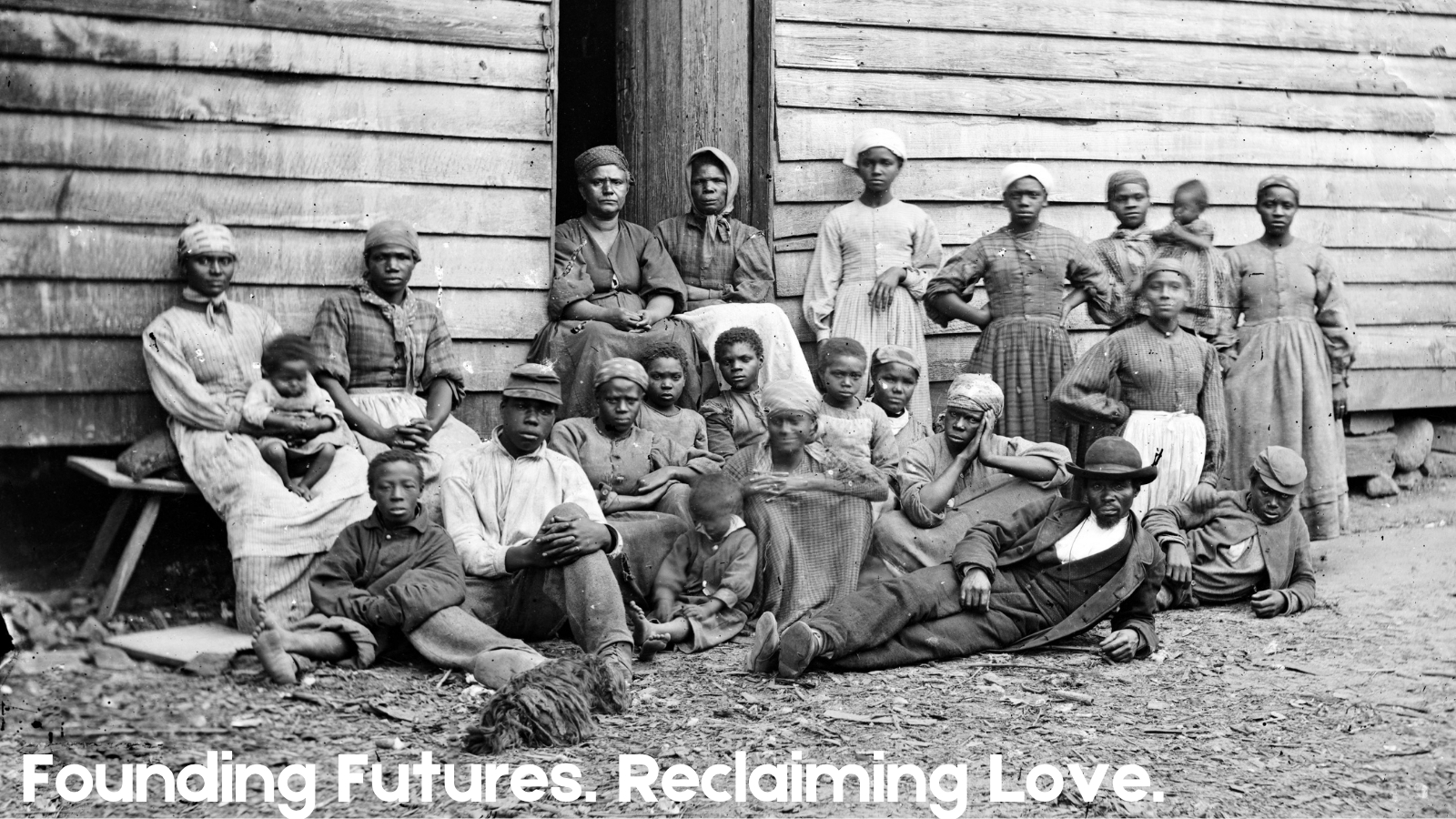 black and white photo from late 1800s of a Black family in front of a wooden wall