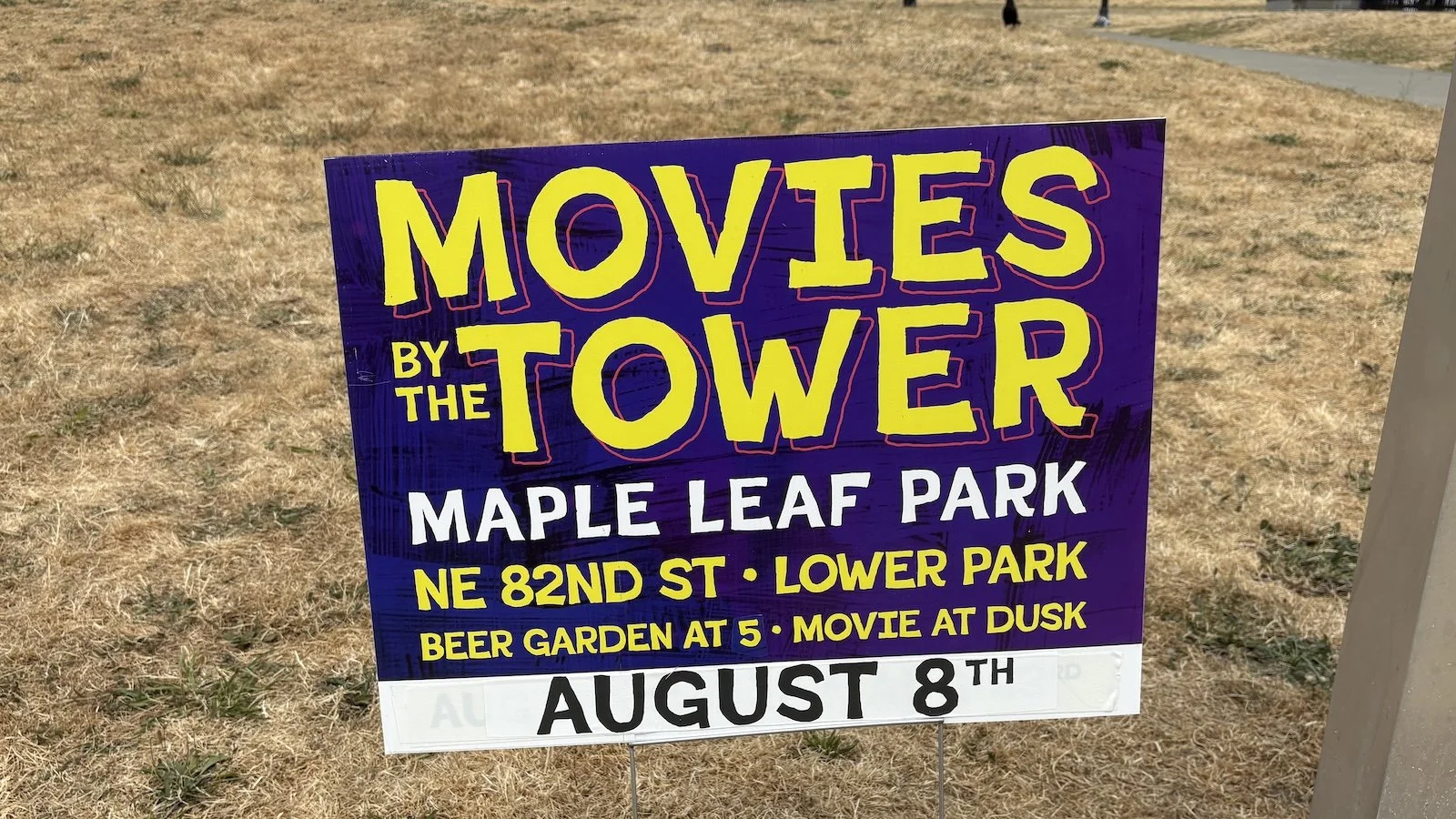 lawn sign "Movies by the Tower" information, yellow and white lettering on a purple background