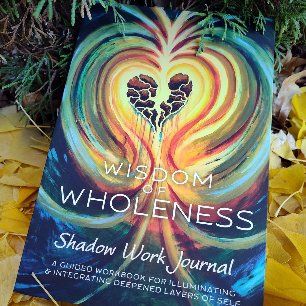 Wisdom of Wholeness Shadow Work Journal sitting on ground with yellow ginko leaves behind it