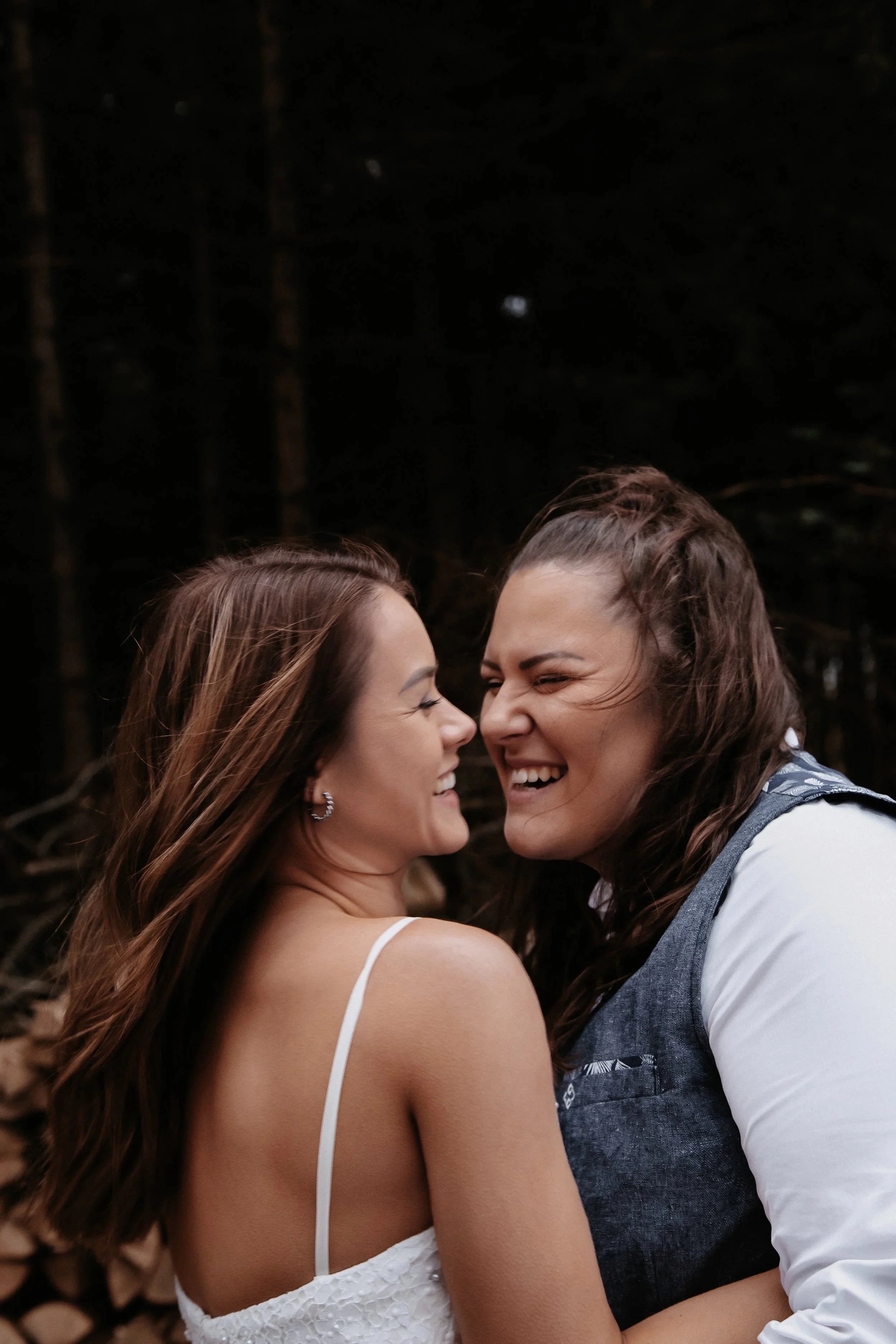 Zwei Frauen lachen und umarmen sich im Freien.