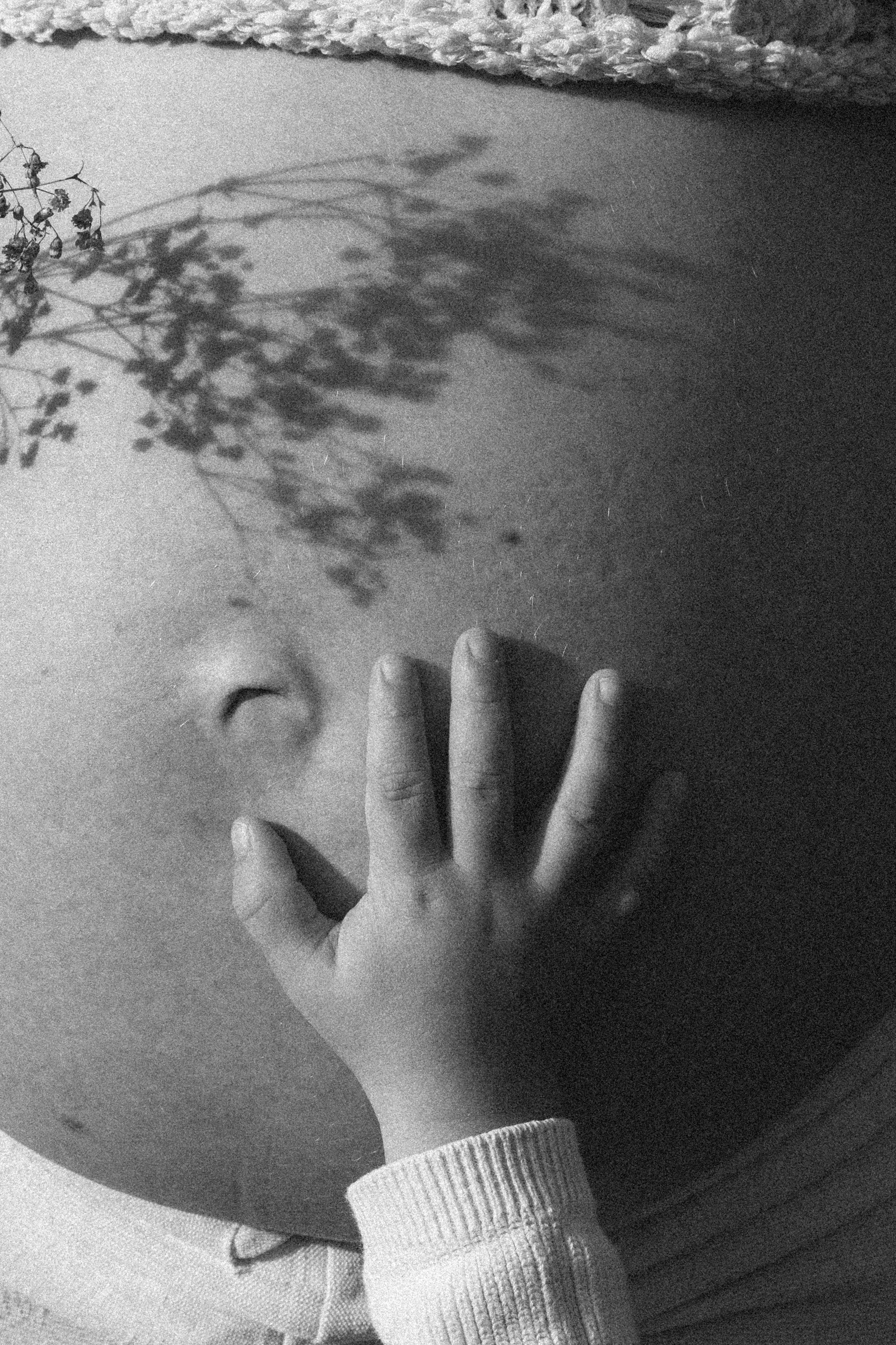 Nahaufnahme eines Menschen, der mit der Hand einen Bereich seiner Wange berührt, im Fokus die Hand und das Gesicht. Das Bild ist schwarz-weiß.