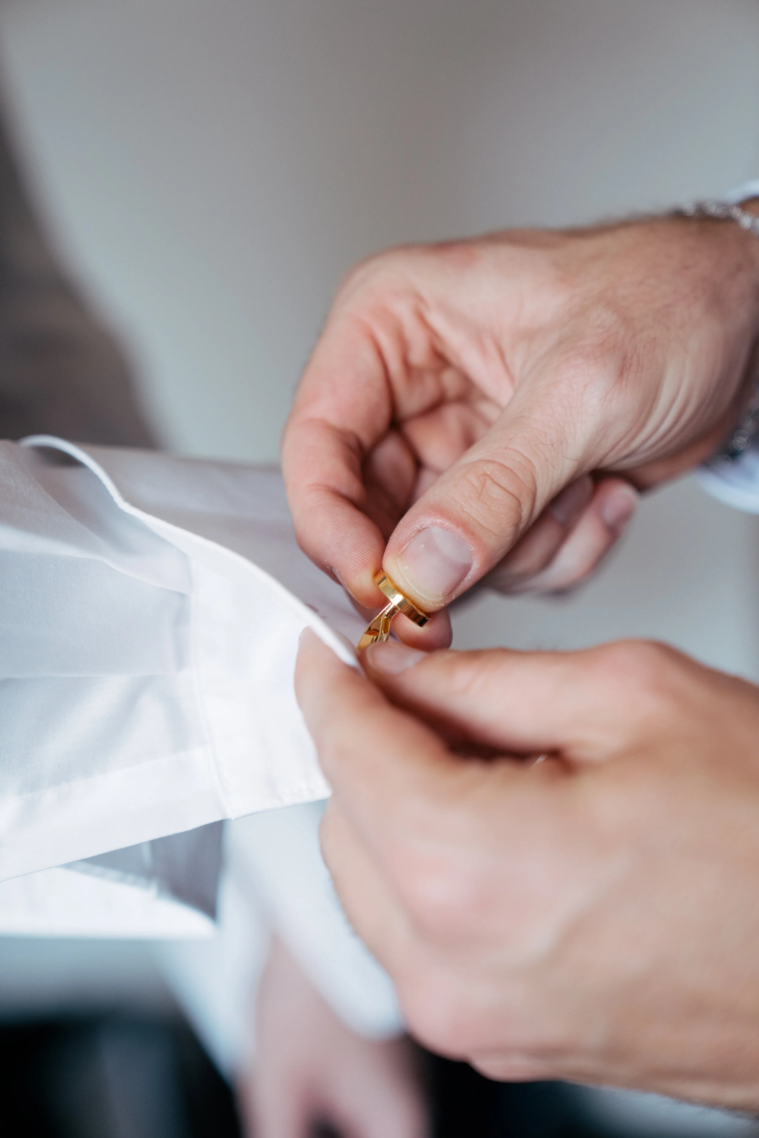 Hand einer Person, die einen goldenen Ring anfertigt, beim Puntieren einer weißen Stoff- oder Kleidungsstücken.