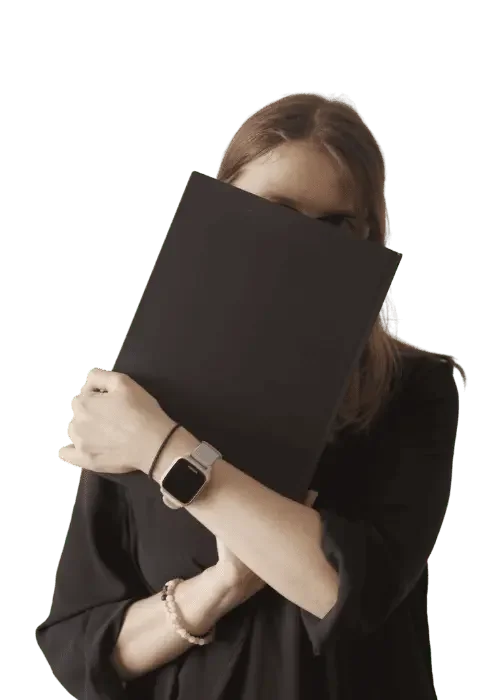 Andrea, hält sich ein Notizbuch vors Gesicht