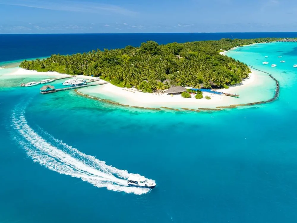 Aerial view of an island in the Maldives, ringed by white sand and a turquoise lagoon