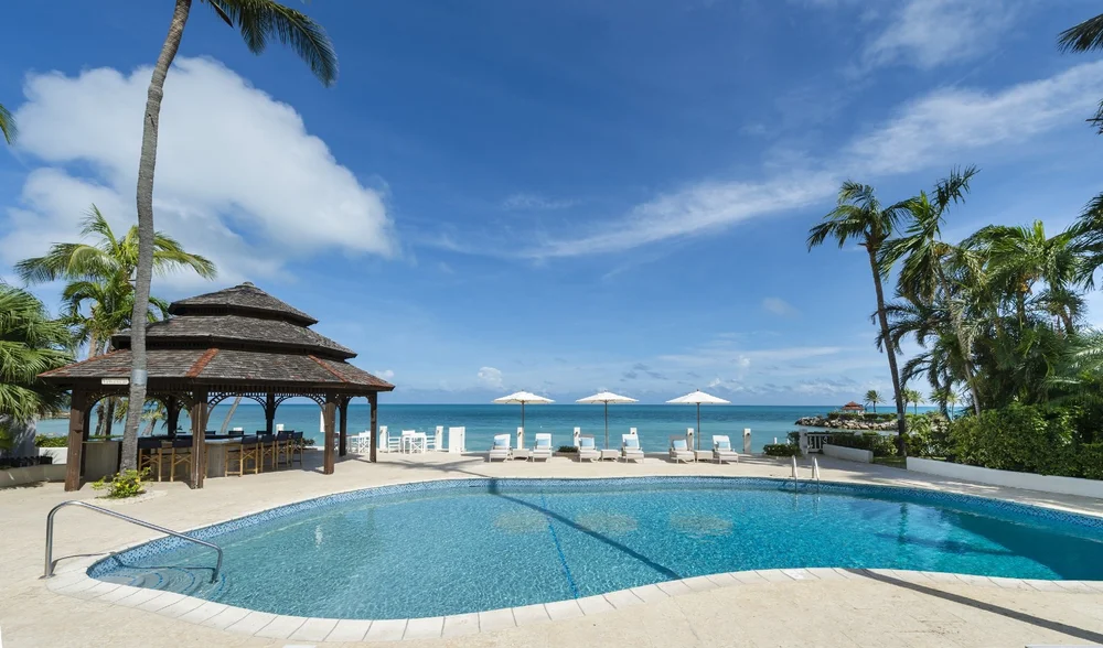 Palm trees, parasols and a pool beside the sea at Blue Waters, Antigua