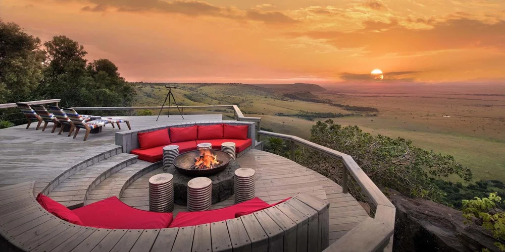 A fire pit lounge at Angama Mara looking out over the Maasai Mara at sunset, Kenya