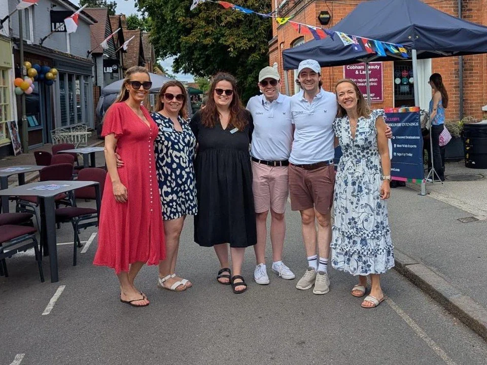 The Huben Travel team standing together on Church Street in Cobham, beneath bunting at a summer street event