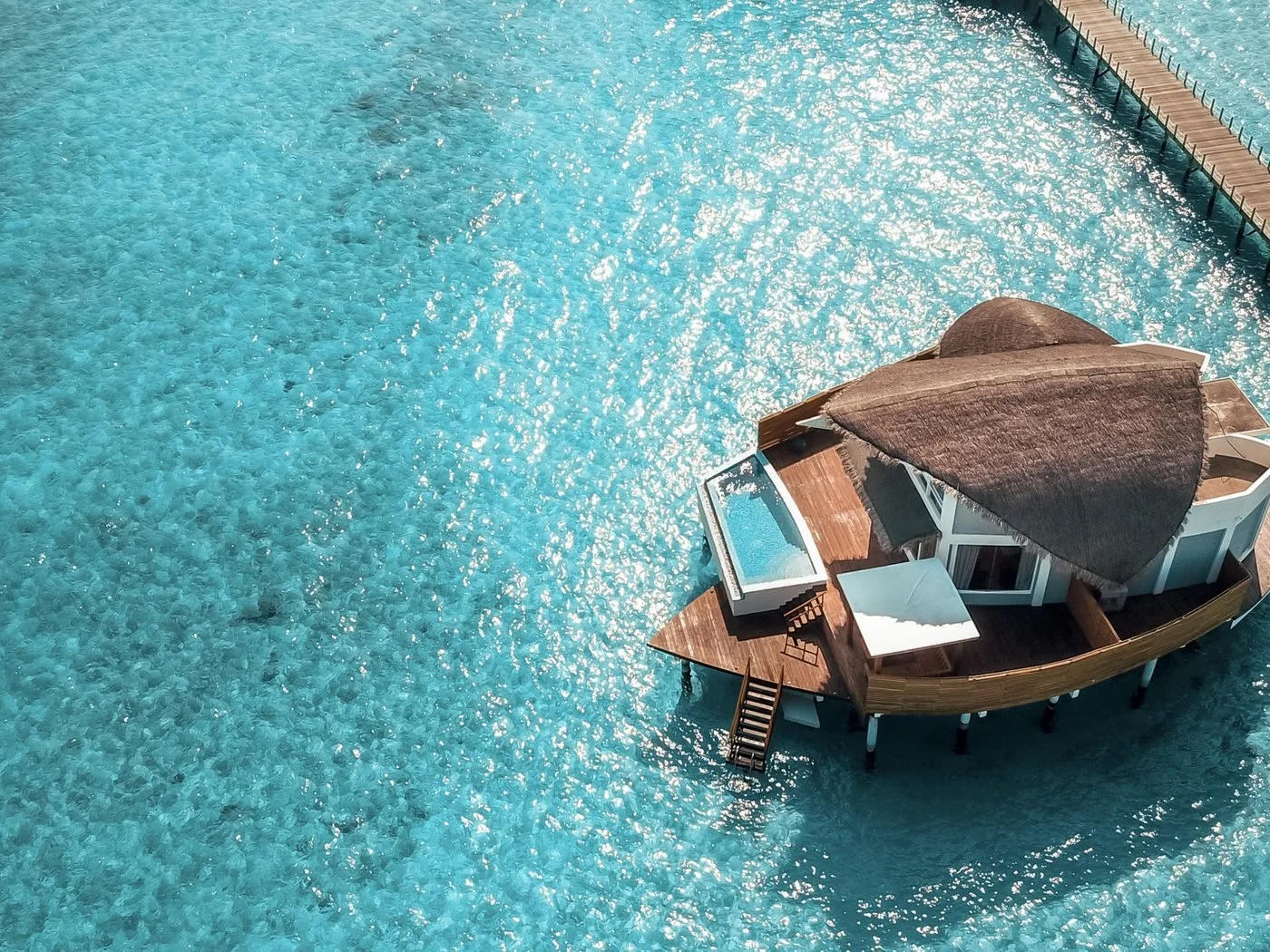 An overwater villa with a private plunge pool above a turquoise lagoon in the Maldives