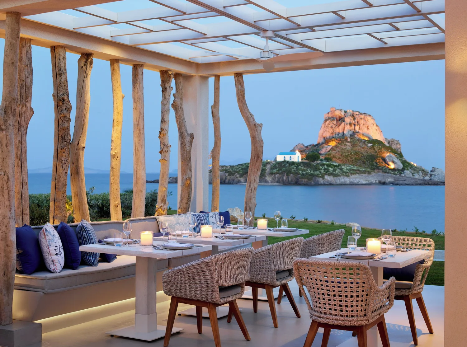 Shaded terrace tables at Ouzo restaurant, Ikos Aria, looking across Kefalos Bay towards Kastri island on Kos