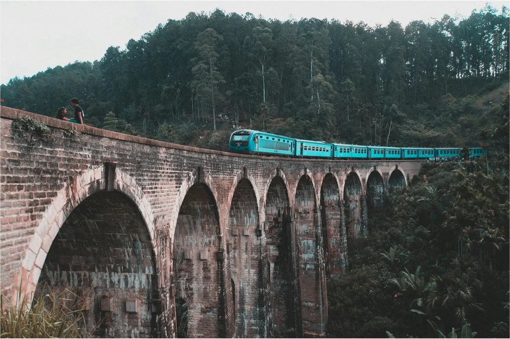 A turquoise train crossing the Nine Arches Bridge near Ella in Sri Lanka's hill country
