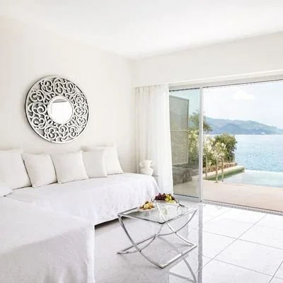 A bright white bedroom with a sofa and a view of the sea